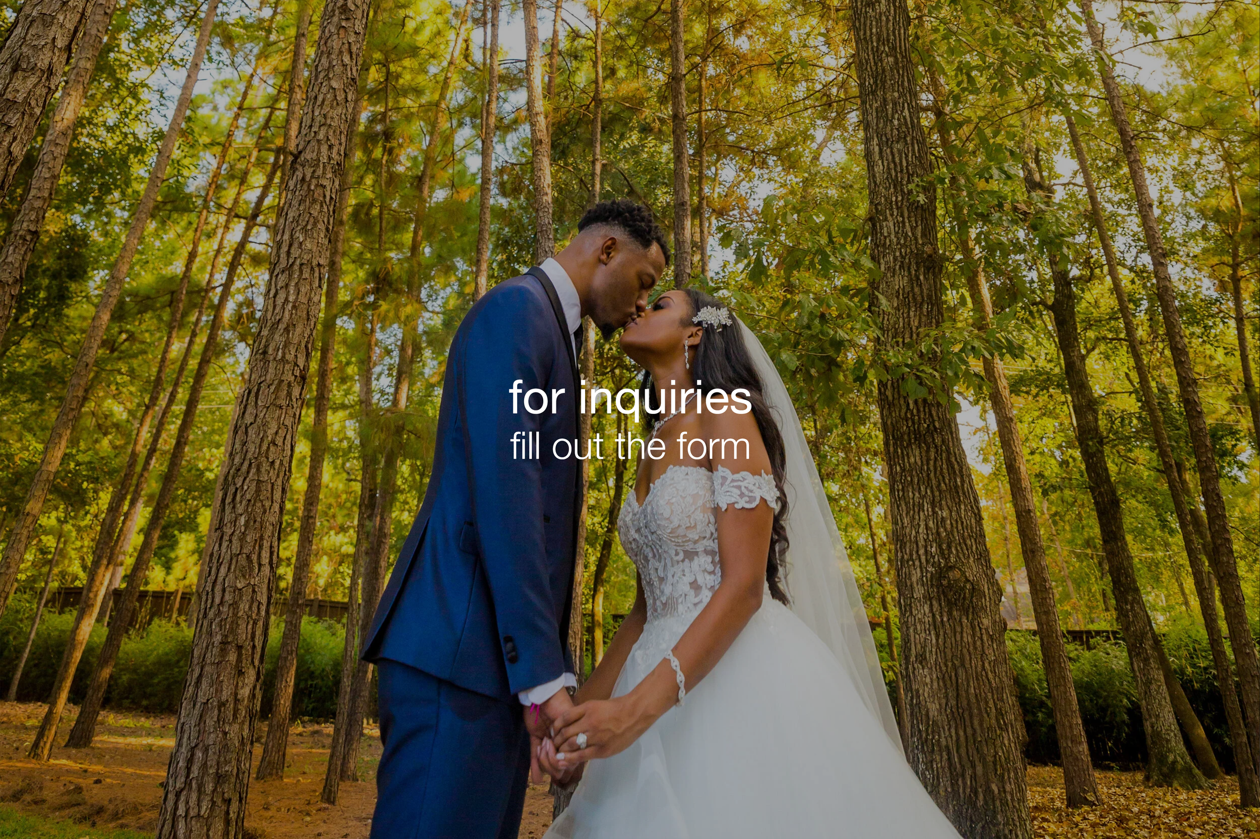 A bride and groom sharing a kiss in a forest setting during daytime, holding hands and dressed in wedding attire.