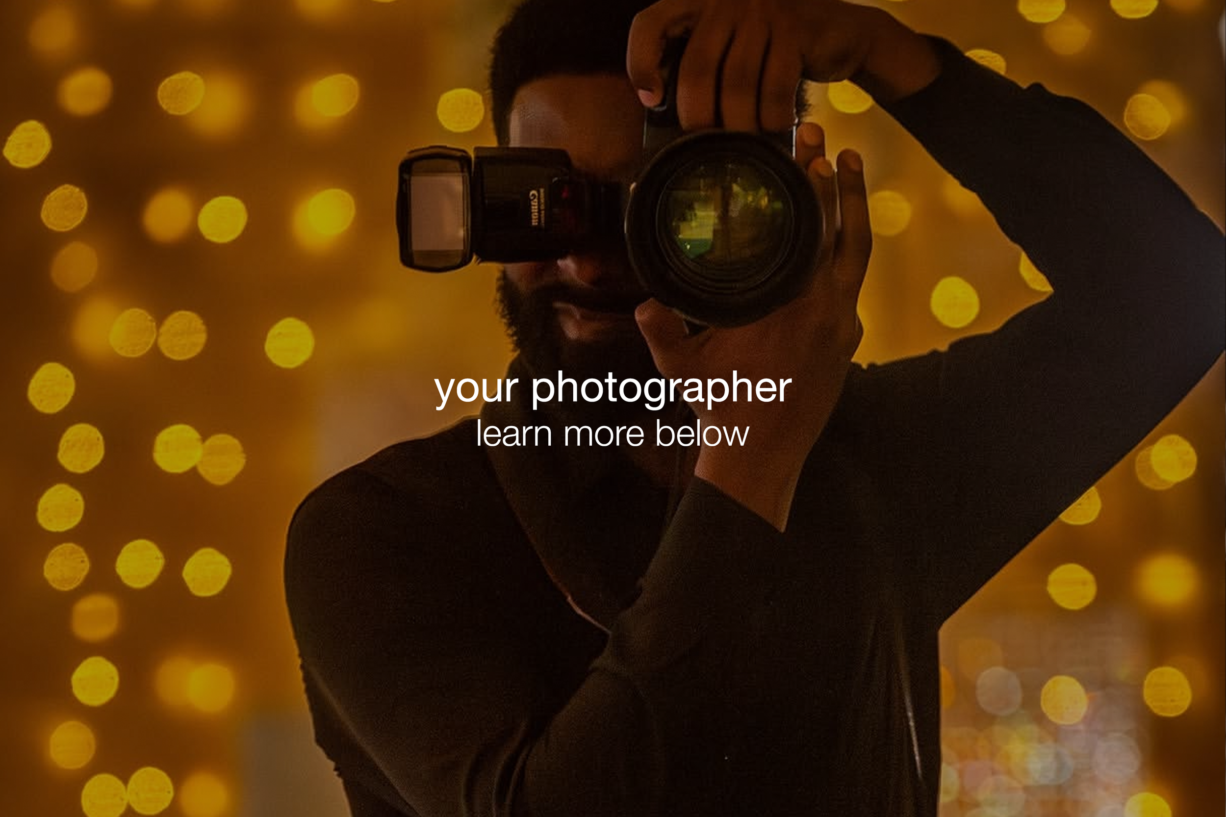 Person taking a photo with a camera, holding it up to their face, standing in front of a background of yellow bokeh lights.
