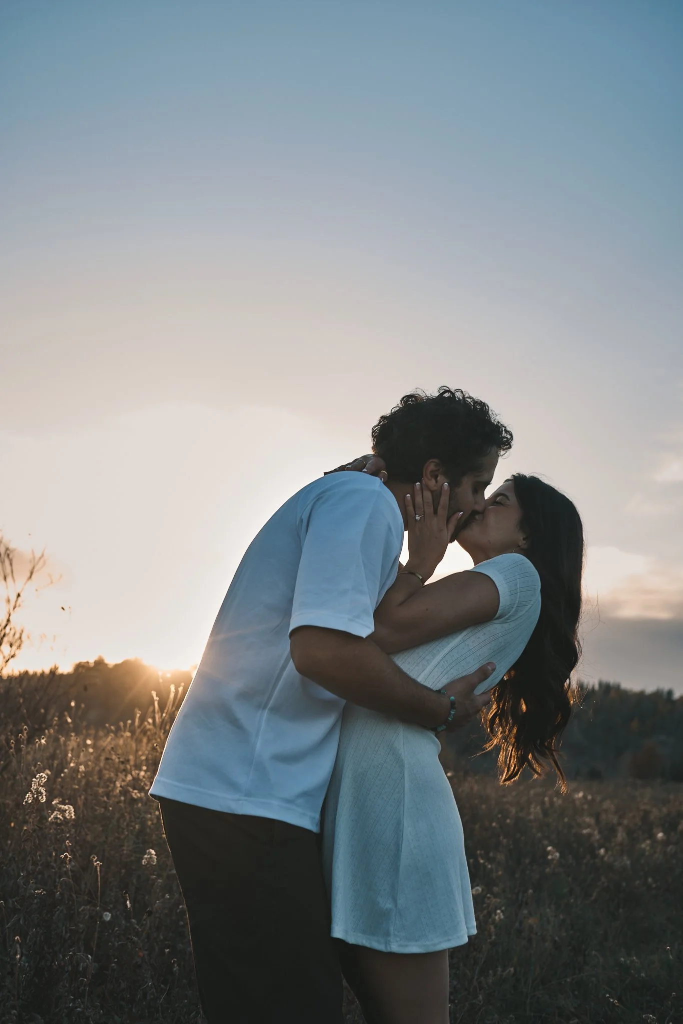 A couple sharing a kiss outdoors at sunset. Taken in Edmonton, Alberta.