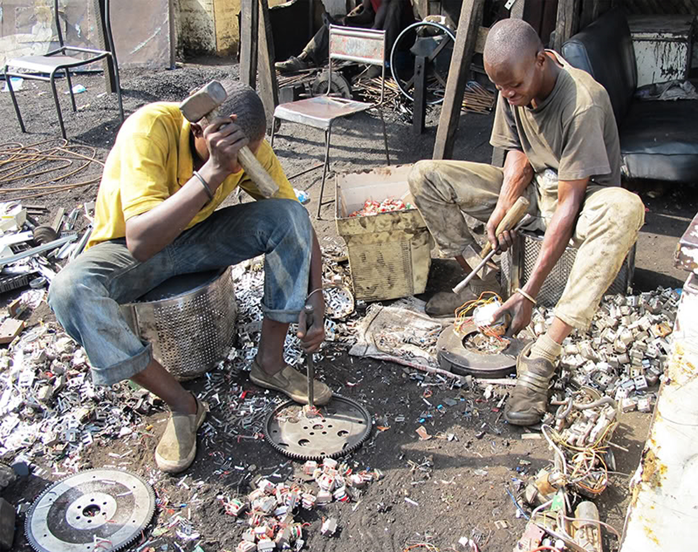 Two people harvest metal scraps from e-waste in Ghana