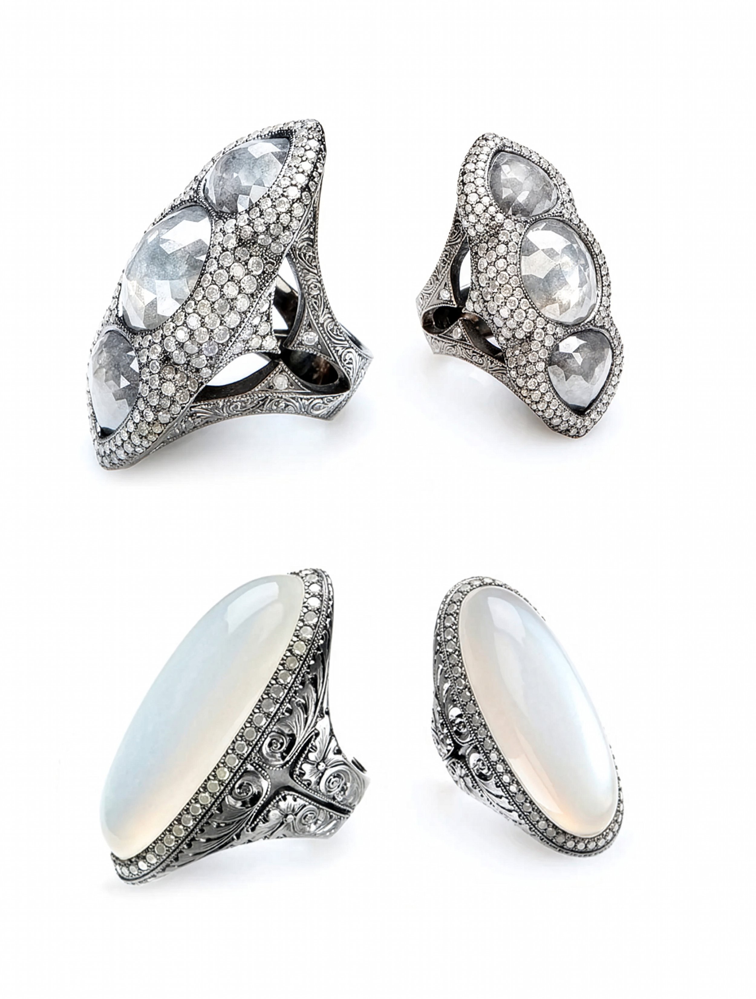 Four ornate rings on a white background: two with faceted, oval clear stones surrounded by pave-set gems, and two with smooth, oval milky stones set in intricate silver bands.