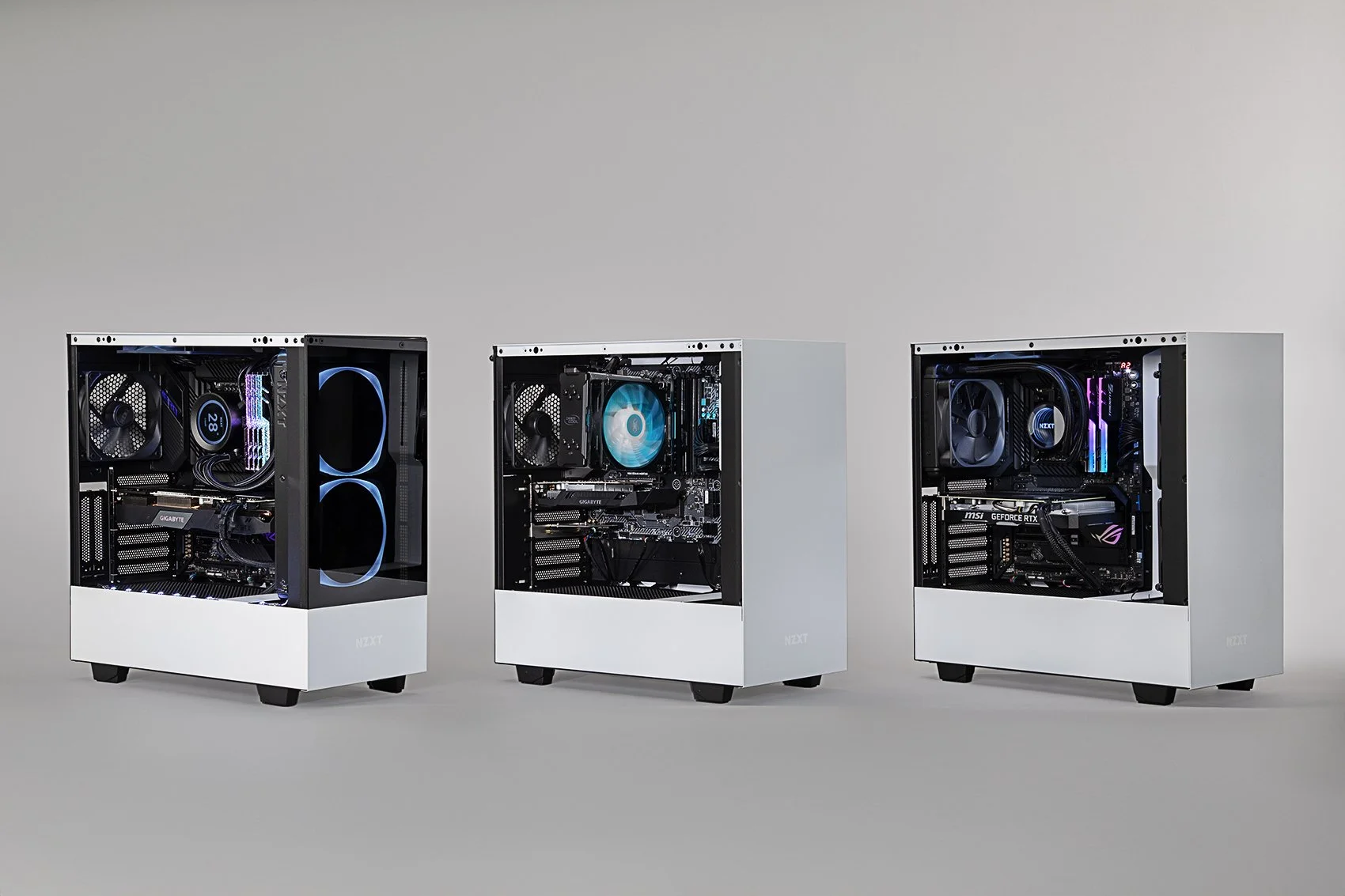 Three white computer towers with transparent side panels displaying internal components, including fans and LED lighting, are lined up against a neutral background.