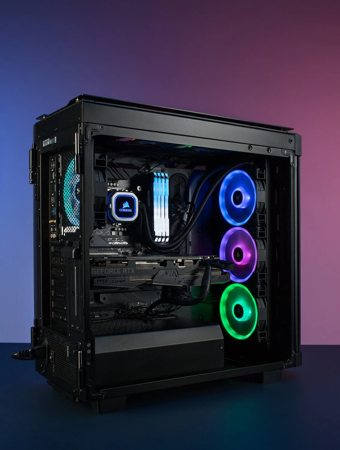 Gaming PC with RGB lighting. The open case reveals components including a graphics card and a cooling system. Three circular fans glow in blue, purple, and green against a gradient pink and blue background.