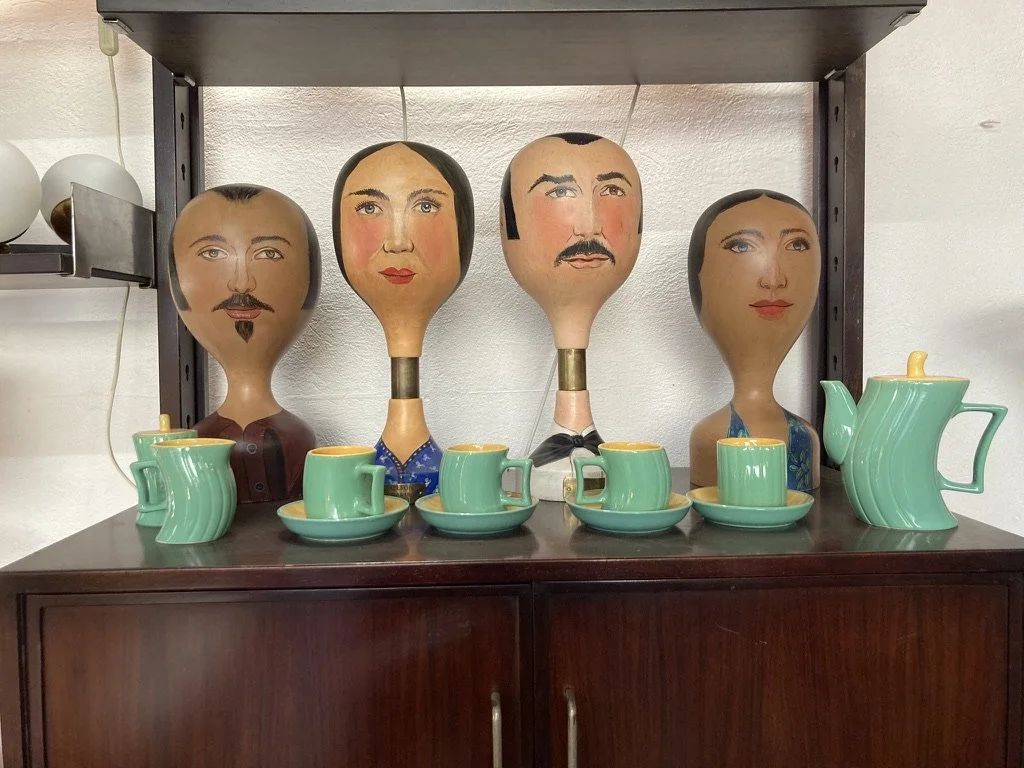 A sideboard, with a vintage green tea set and 4 wooden head busts.