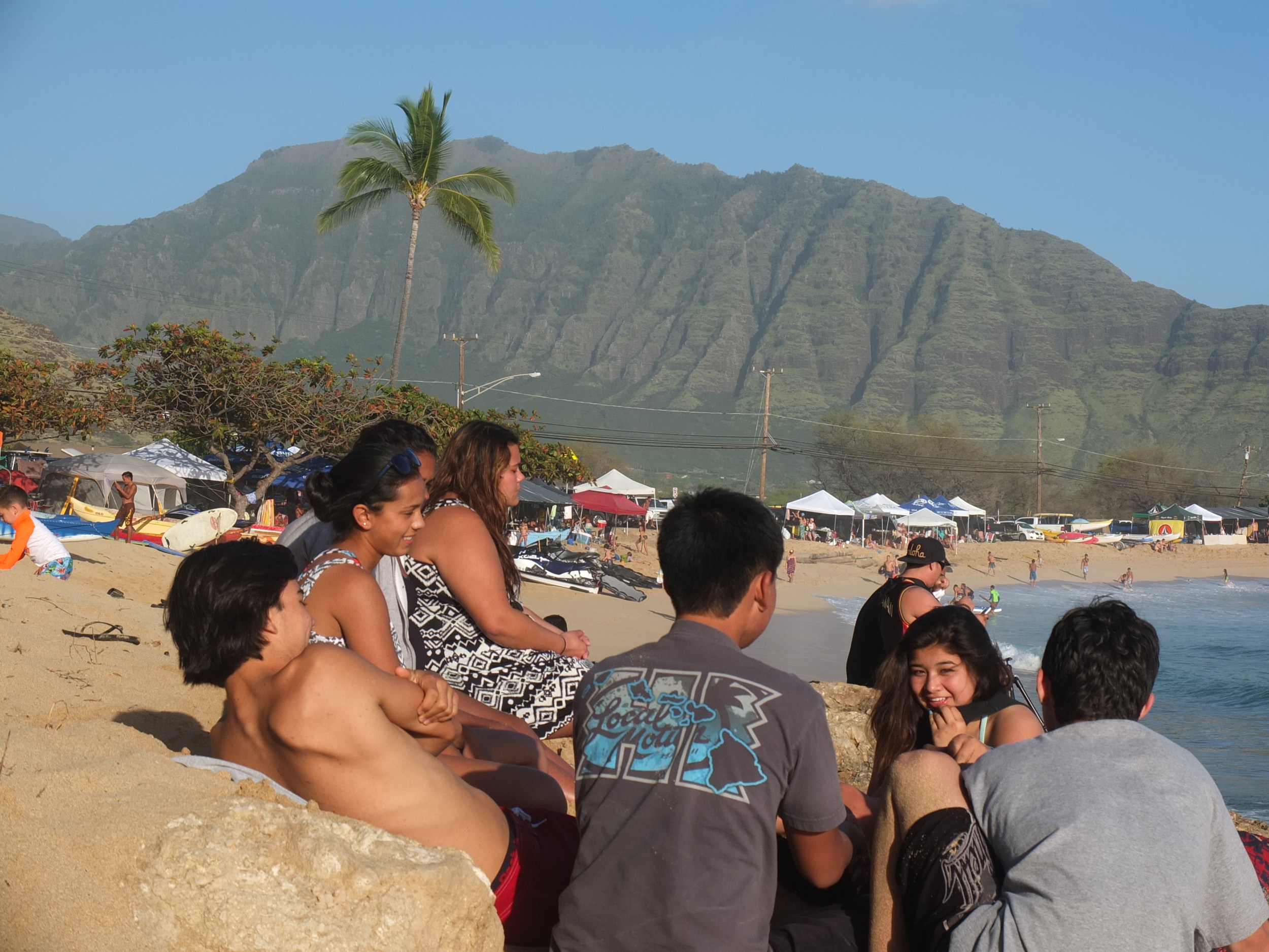Na Kama Kai Youth exchange some social time during the Buffalo Big Board Classic in Makaha. This legendary contest, gathering, is the oldest surf contest in the world and brings ultimate prestige in water sports. Today the waves were over 20ft so youth talked story and watched from the beach.