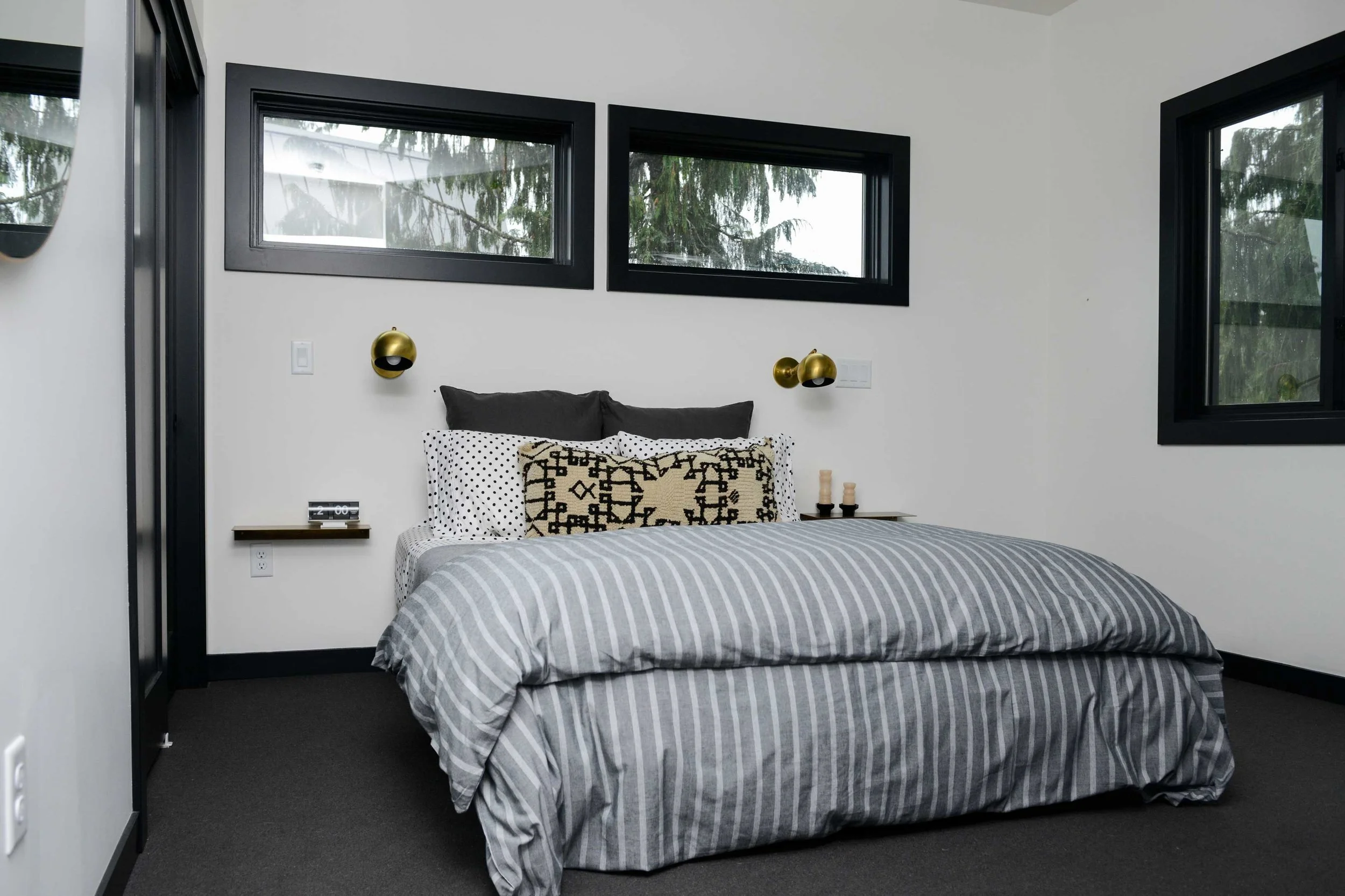Above: We kept the master simple: white walls, black trim and black carpet. Sconces and bedding from Schoolhouse Electric . Lumbar pillow from Kat + Maouche . 