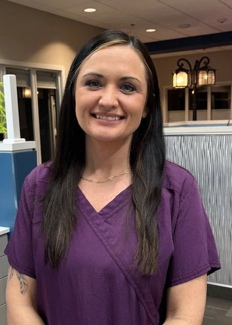 Photo of Natasha smiling in purple scrubs.