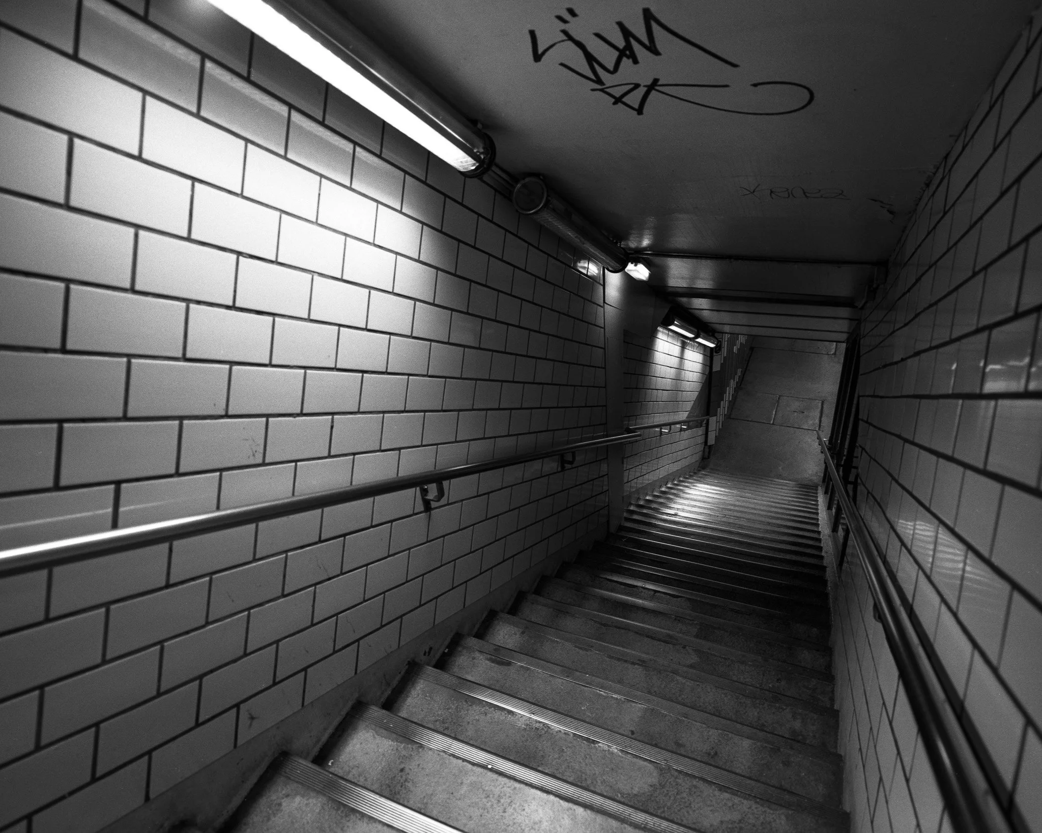 Black-and-white photograph of stairs descending into the metro, Paris.