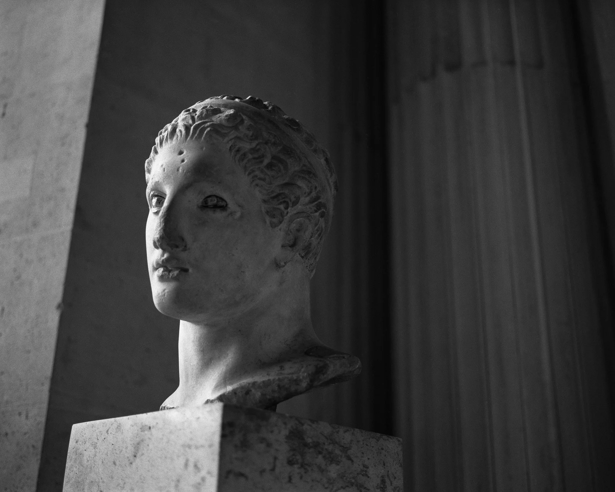 Black-and-white street photograph showing a sculpture in the Louvre, Paris.