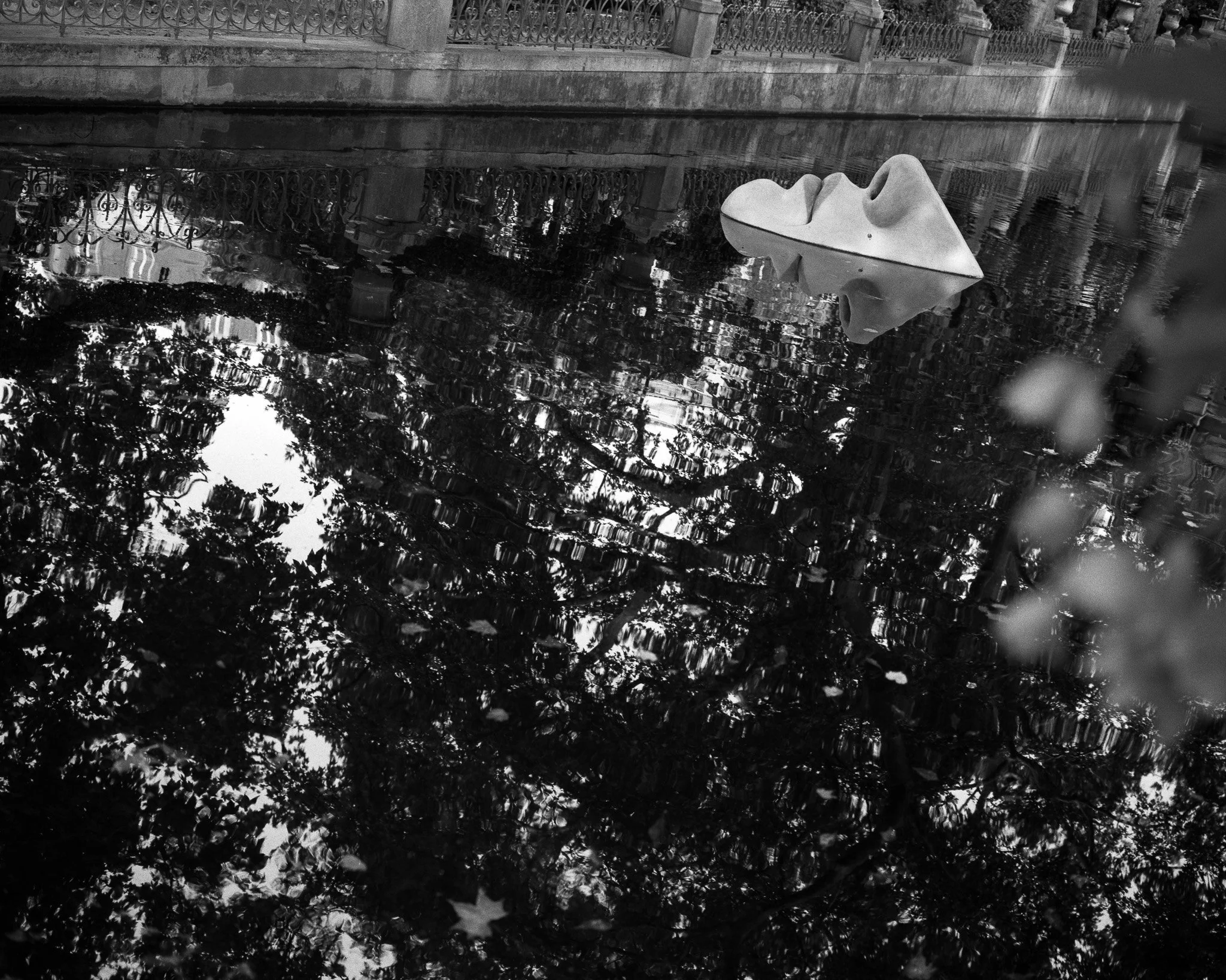 Black-and-white photograph of a sculpture in a pond, Paris.