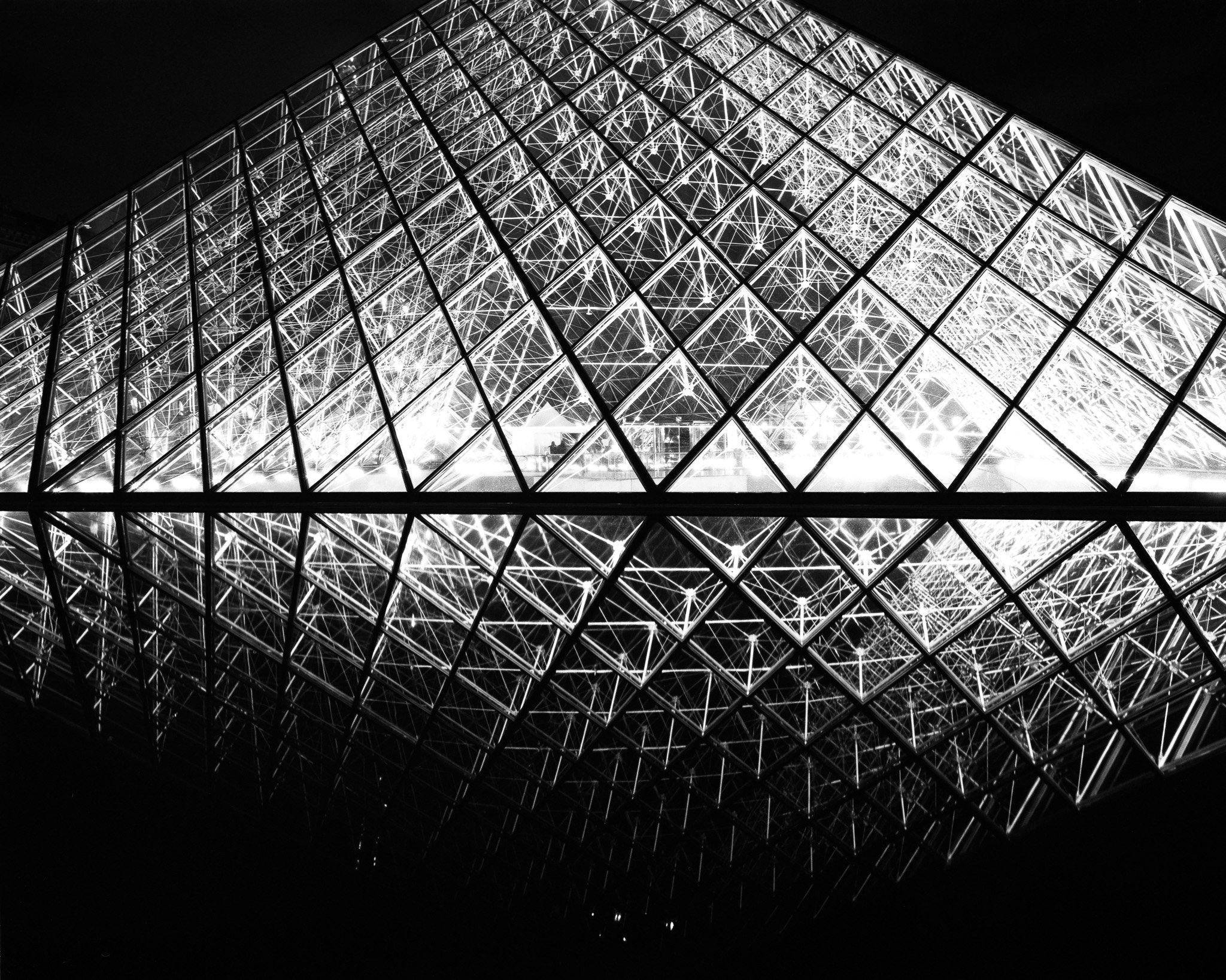 Black-and-white photograph of the Louvre pyramid in Paris.