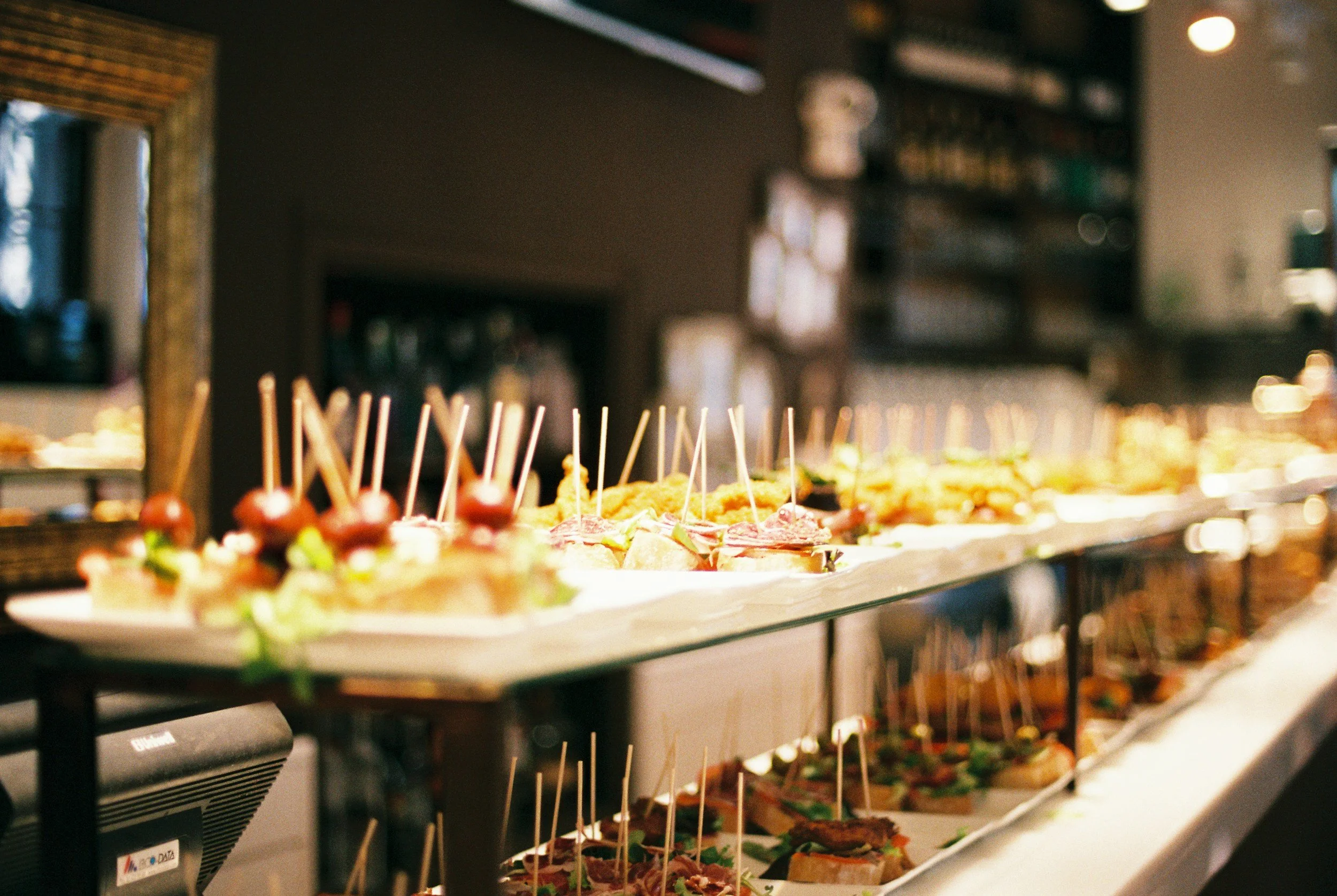 A variety of appetizers and finger foods with toothpicks on display at a buffet or catering setup in a restaurant or event space. - Catering Chef Kansas City