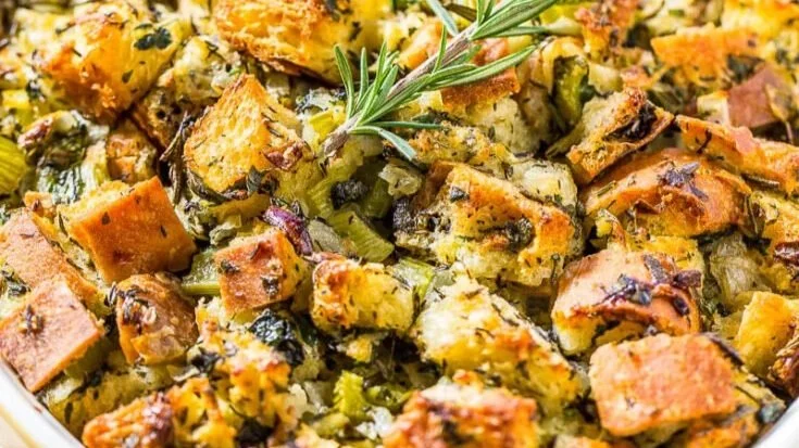 Baked stuffing with chunks of bread, celery, herbs, and a sprig of rosemary on top. - Catering Chef Kansas City
