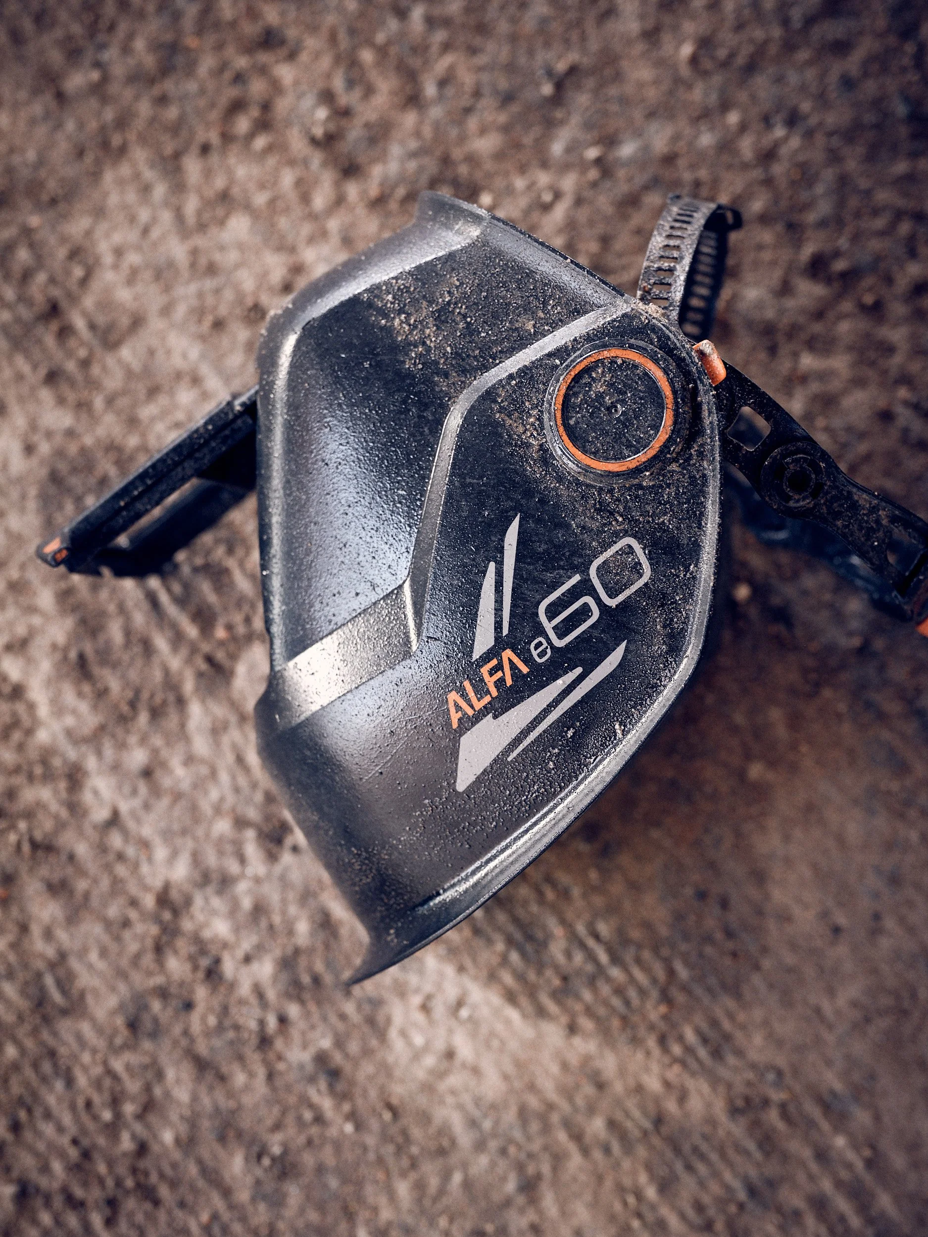 Close-up of a dirt-covered water jet helmet lying on the ground