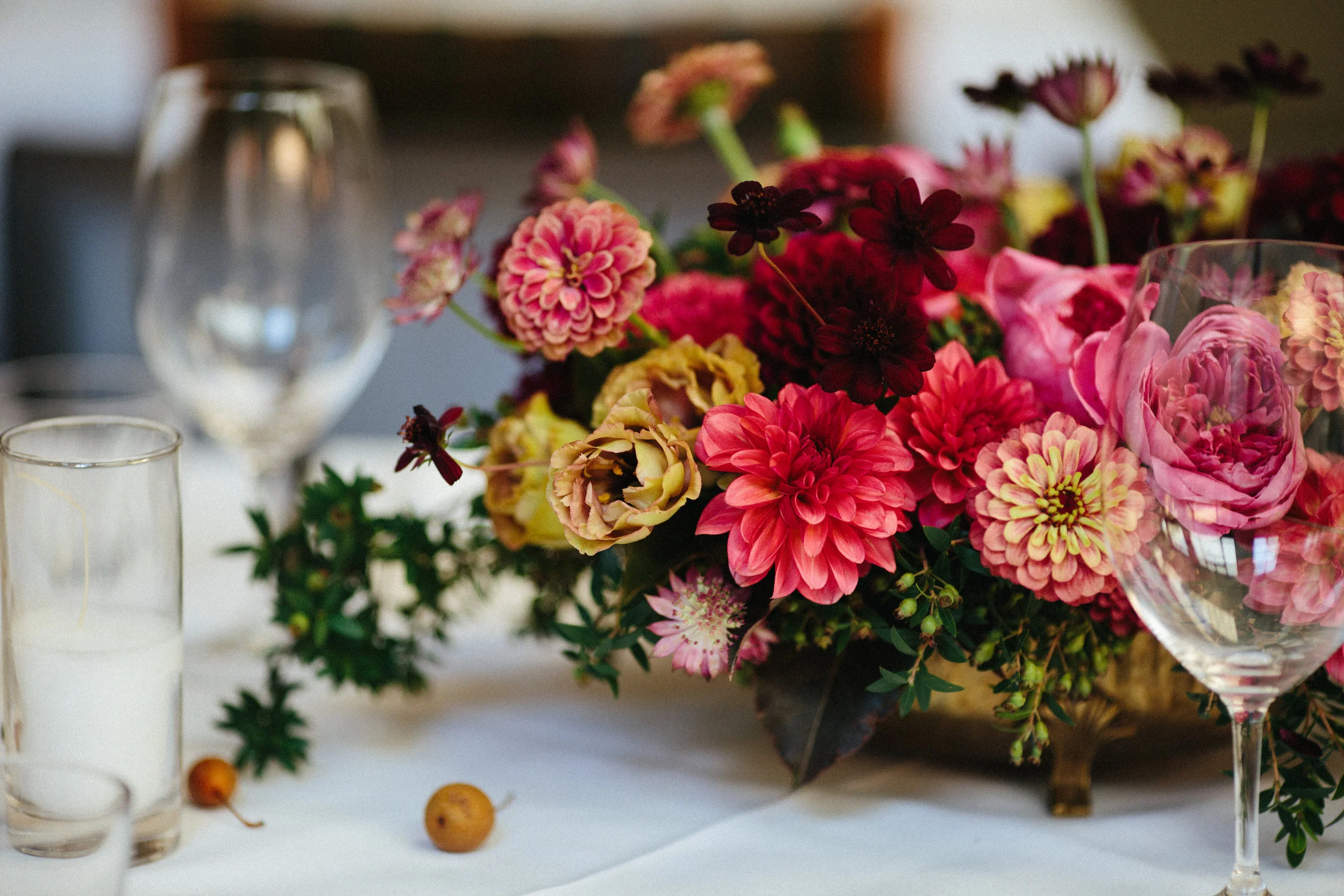 Photo by Diana Rothery . Lush jewel tone centerpiece with queen red lime zinnias, burgundy dahlias, roseanne brown lisianthus, and chocolate cosmos. Venue: Foreign Cinema in San Francisco.