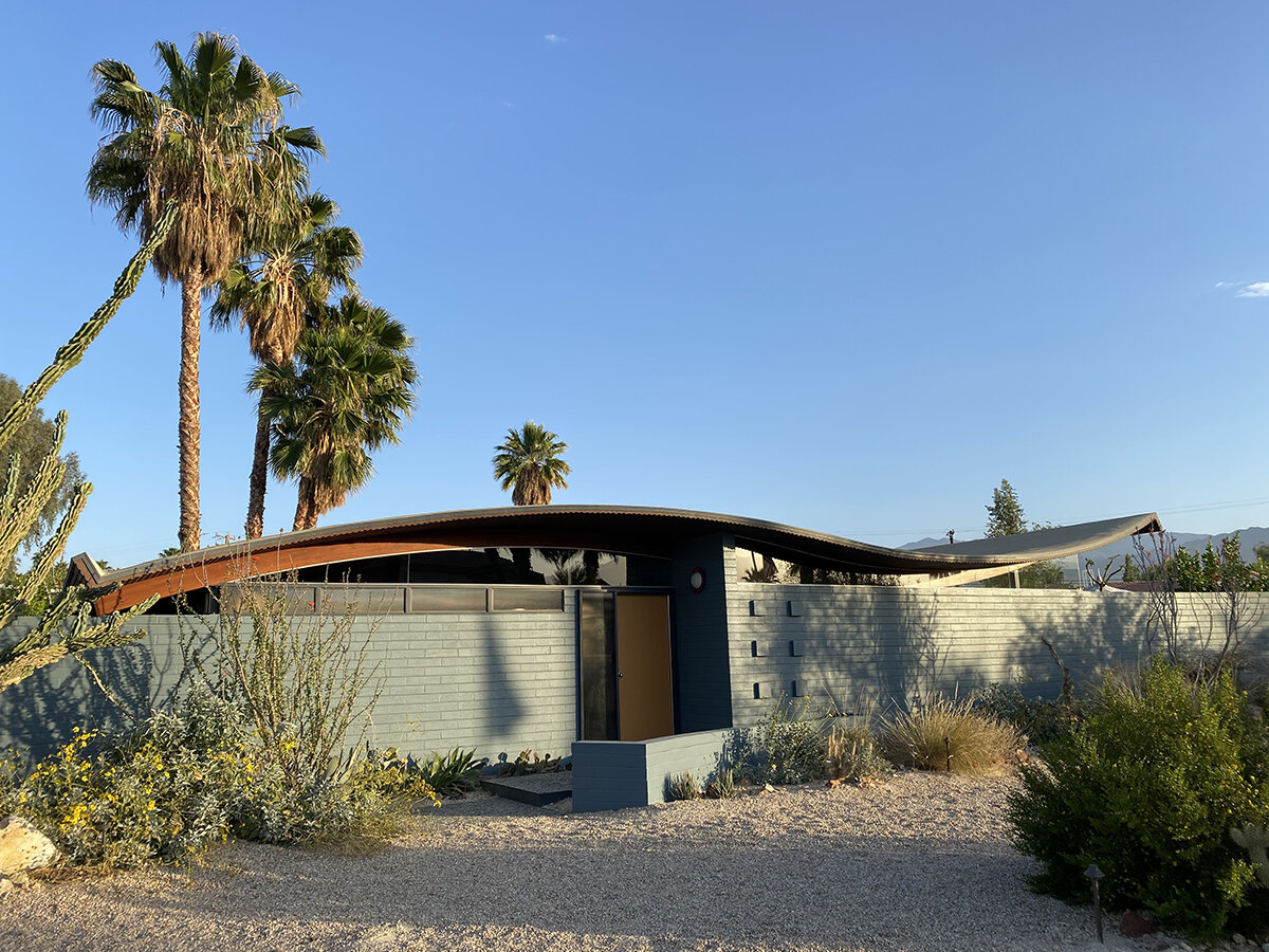  Miles C. Bates   Wave House  Restored by Stayner Architects. A low, modern building with a curved roof, surrounded by desert and palm trees.  