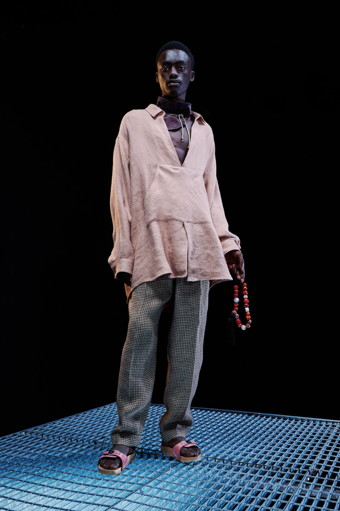  Model wears pink top and slides with grey trousers for Magliano's Spring/Summer 2022 collection for Milan Fashion Week. 
