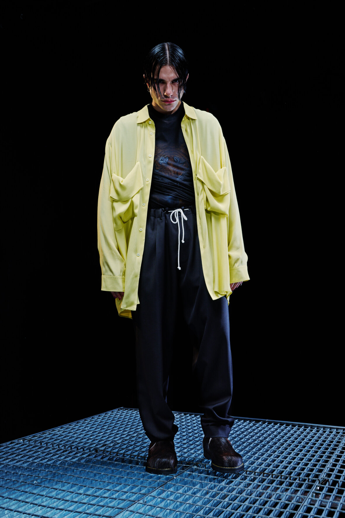 Model wears oversized yellow jacket over dark shirt and pants for Magliano's Spring/Summer 2022 collection for Milan Fashion Week. 