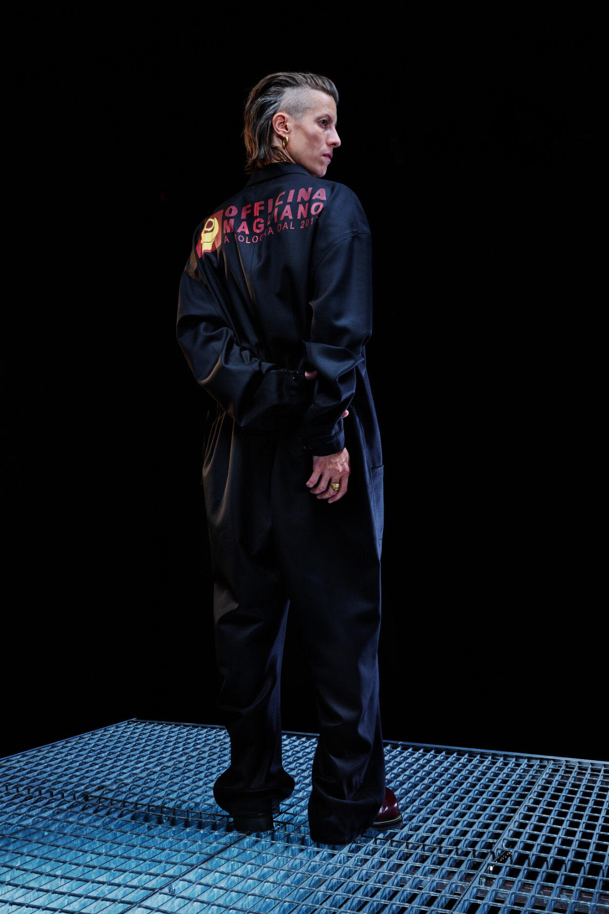  Model wears baggy black suit with text on back for Magliano's Spring/Summer 2022 collection for Milan Fashion Week. 