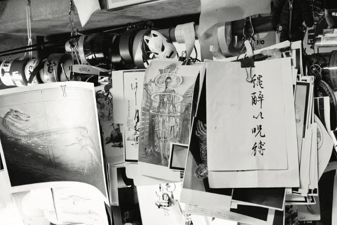 Black and white photo of multiple paper art pieces hung up on clips