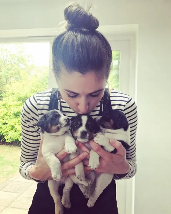 Photo of health and wellness coach Georgie Muir with 3 puppies in her arms
