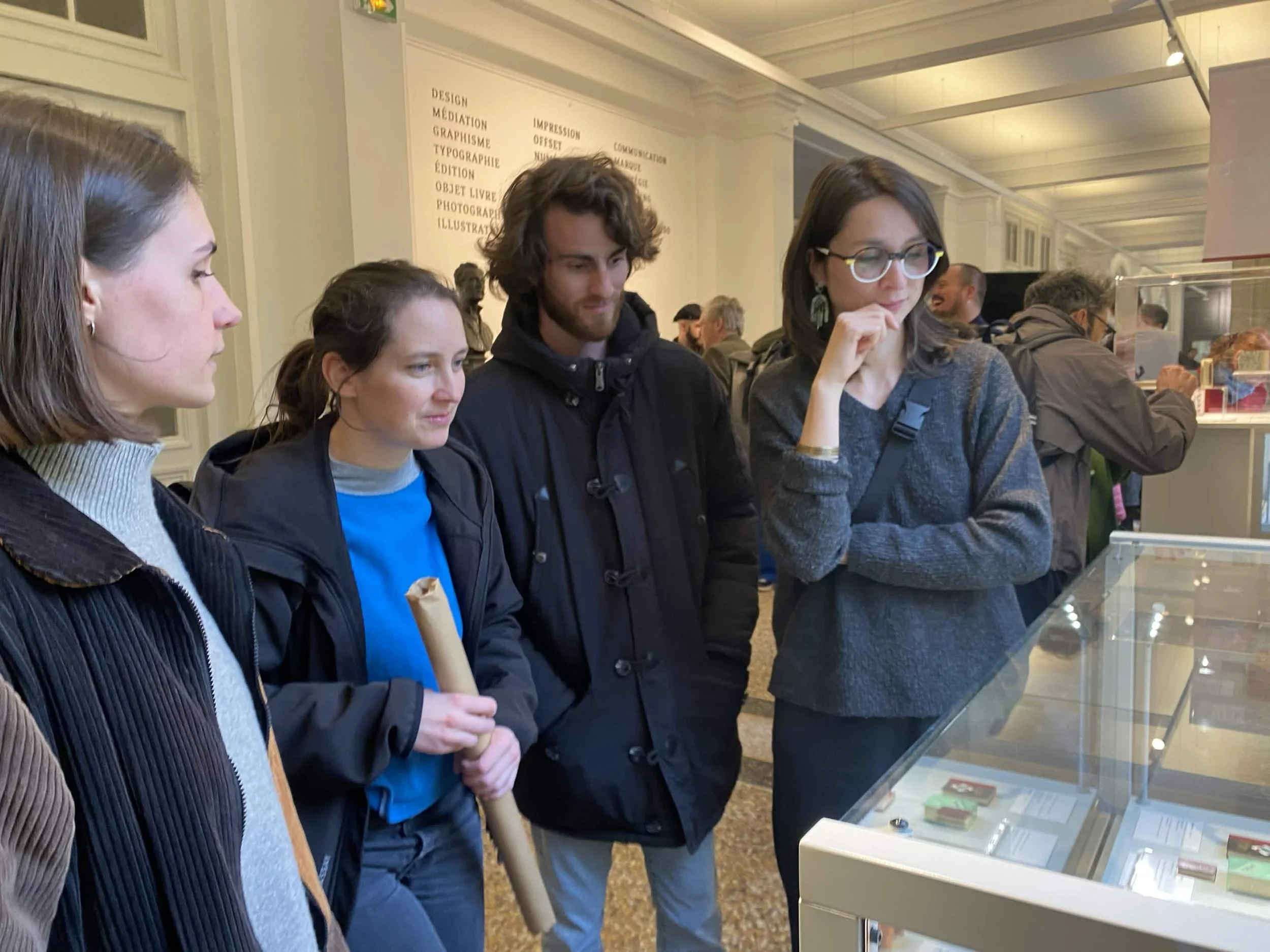 Elise, Paula et Anaïde regardent une vitrine de l'exposition Small Wonders à l'Ecole Estienne