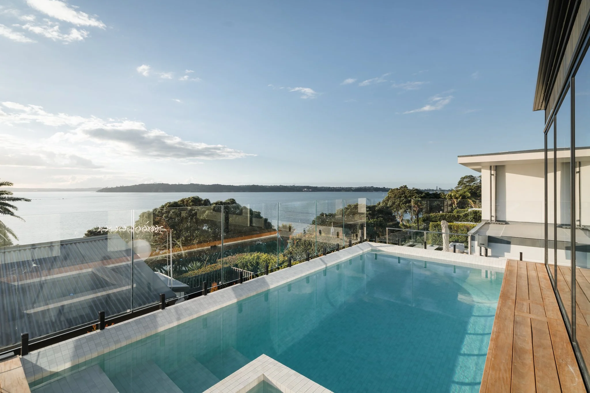 Tiled infinity pool and spa, with floor to ceiling windows dividing the dining room and kitchen.