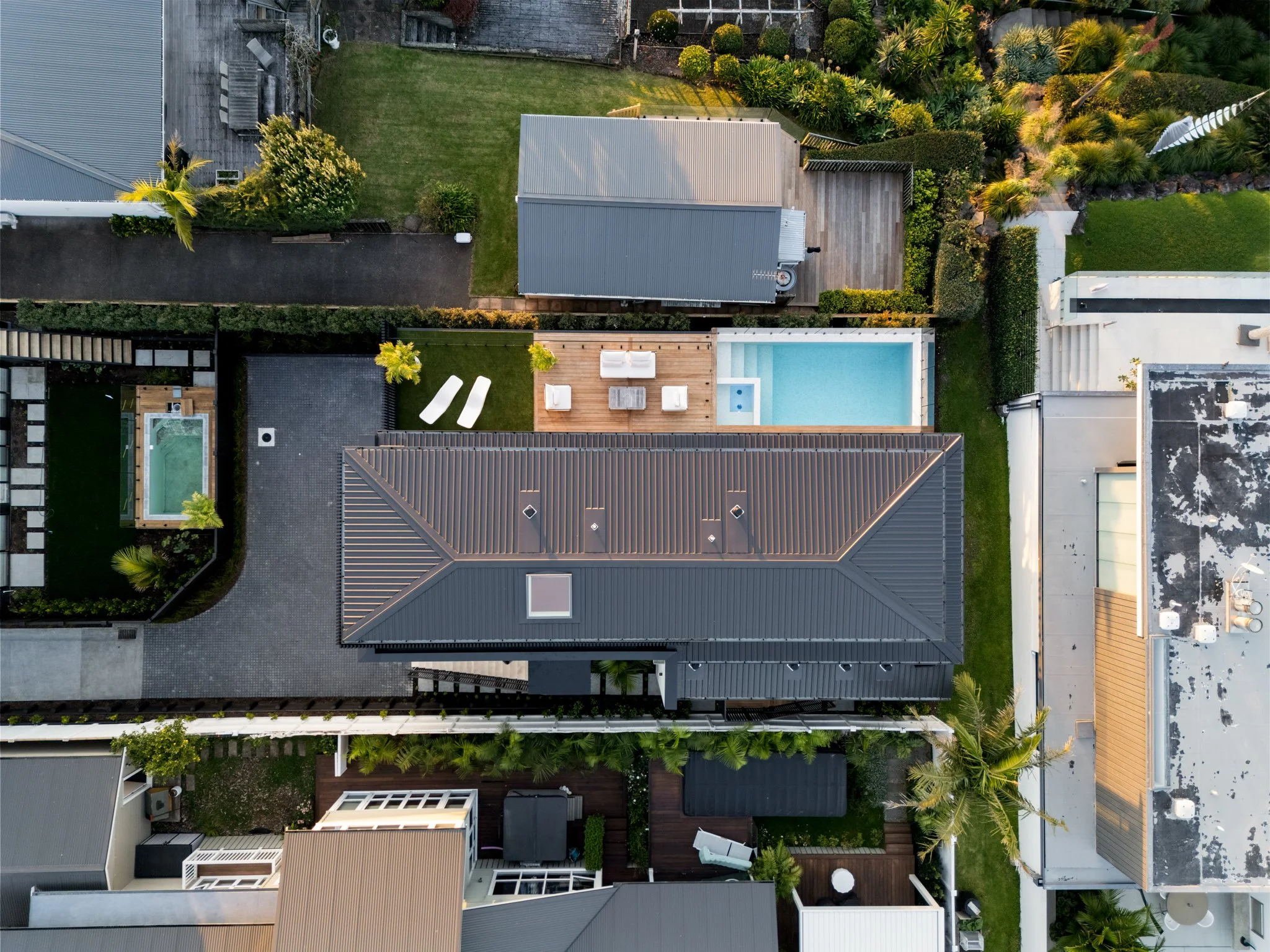 Aerial view of new-build with tiled infinity pool and white outdoor furniture.