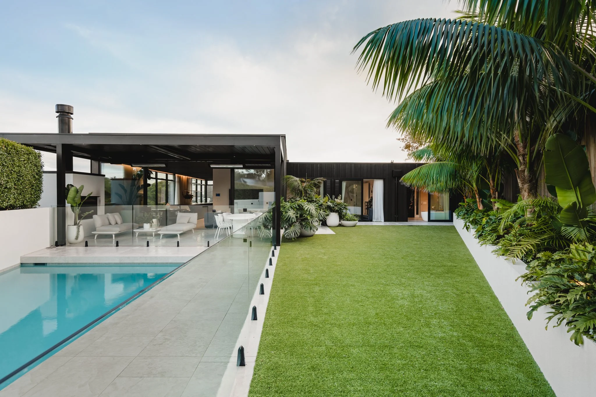 St Heliers House | Bespoke New-Build Featuring outdoor fireplace and LOUVRETEC. Exterior clad in black vertical cedar and landscaped garden by Xanthe White.