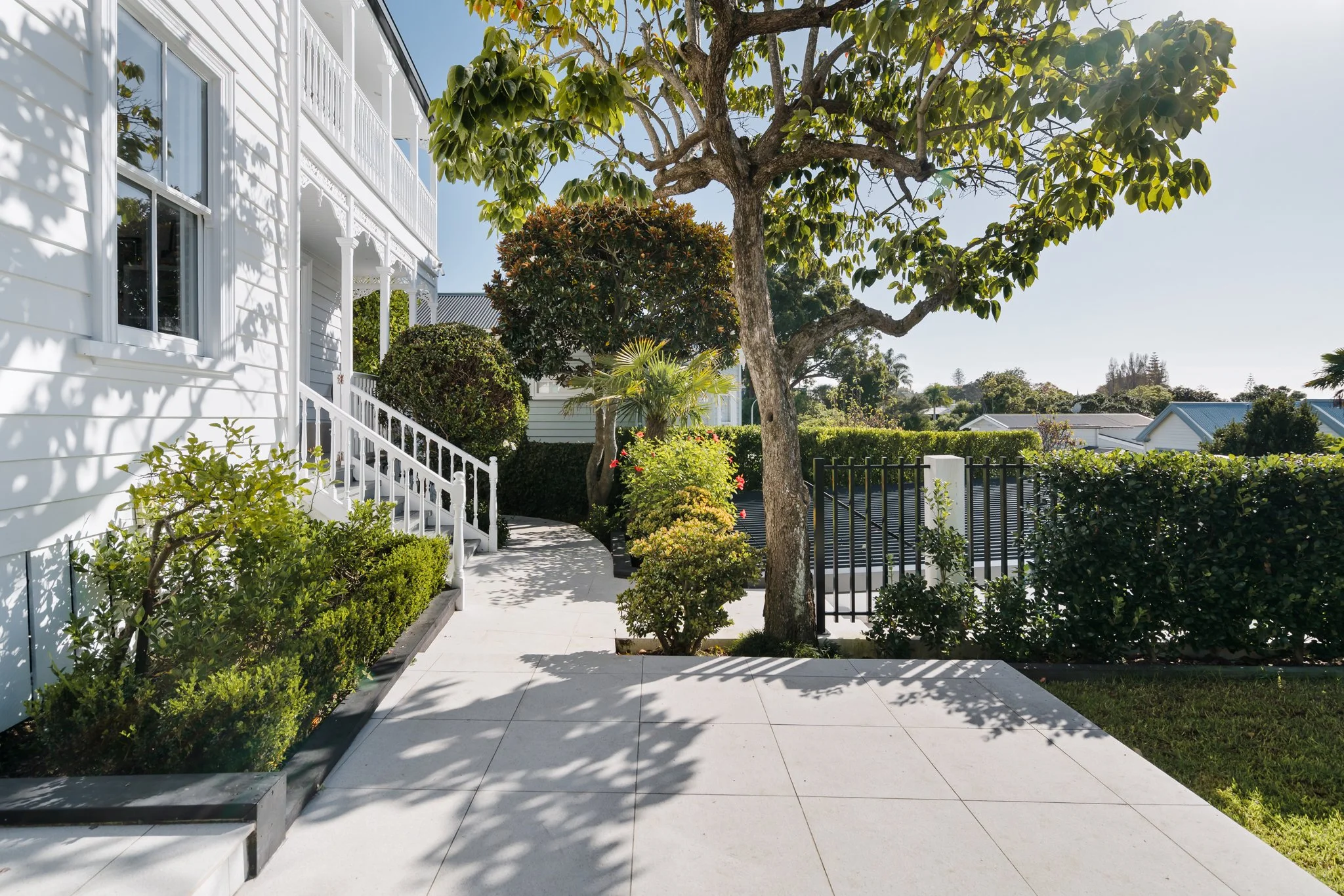 Freemans Bay double villa front garden renovation — large format pavers, iron gated entry, clipped hedging and original villa verandah by Macfie Architecture Auckland
