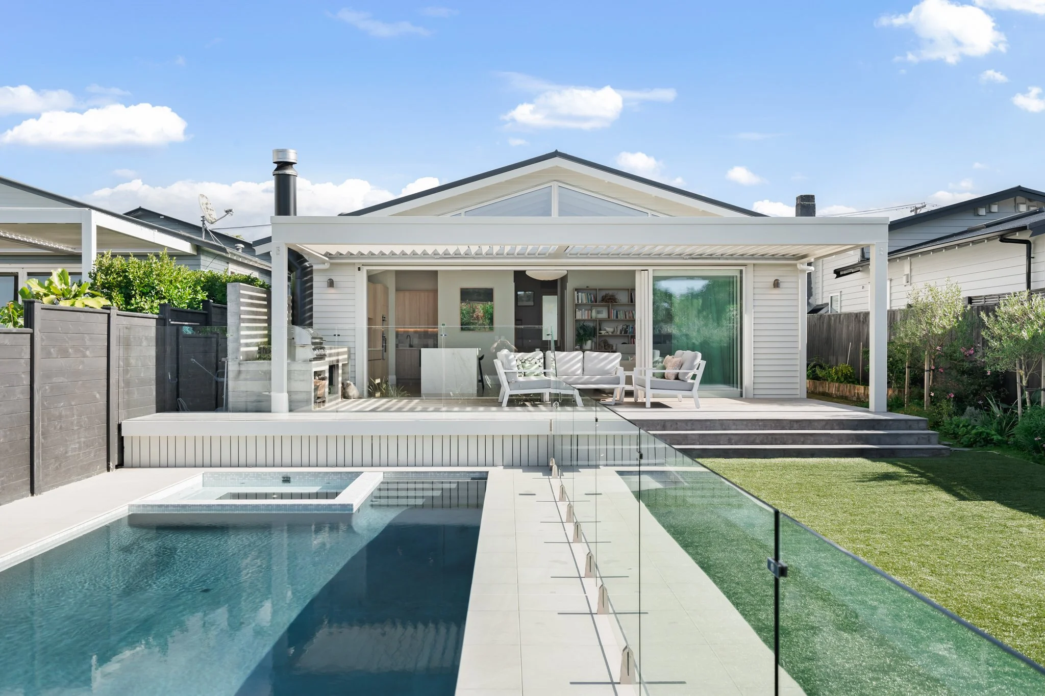 Outdoor entertaining deck with louvre pergola, outdoor kitchen, concrete fireplace, spa and saltwater pool — 1920s Point Chevalier Californian bungalow renovation by Macfie Architecture Auckland.