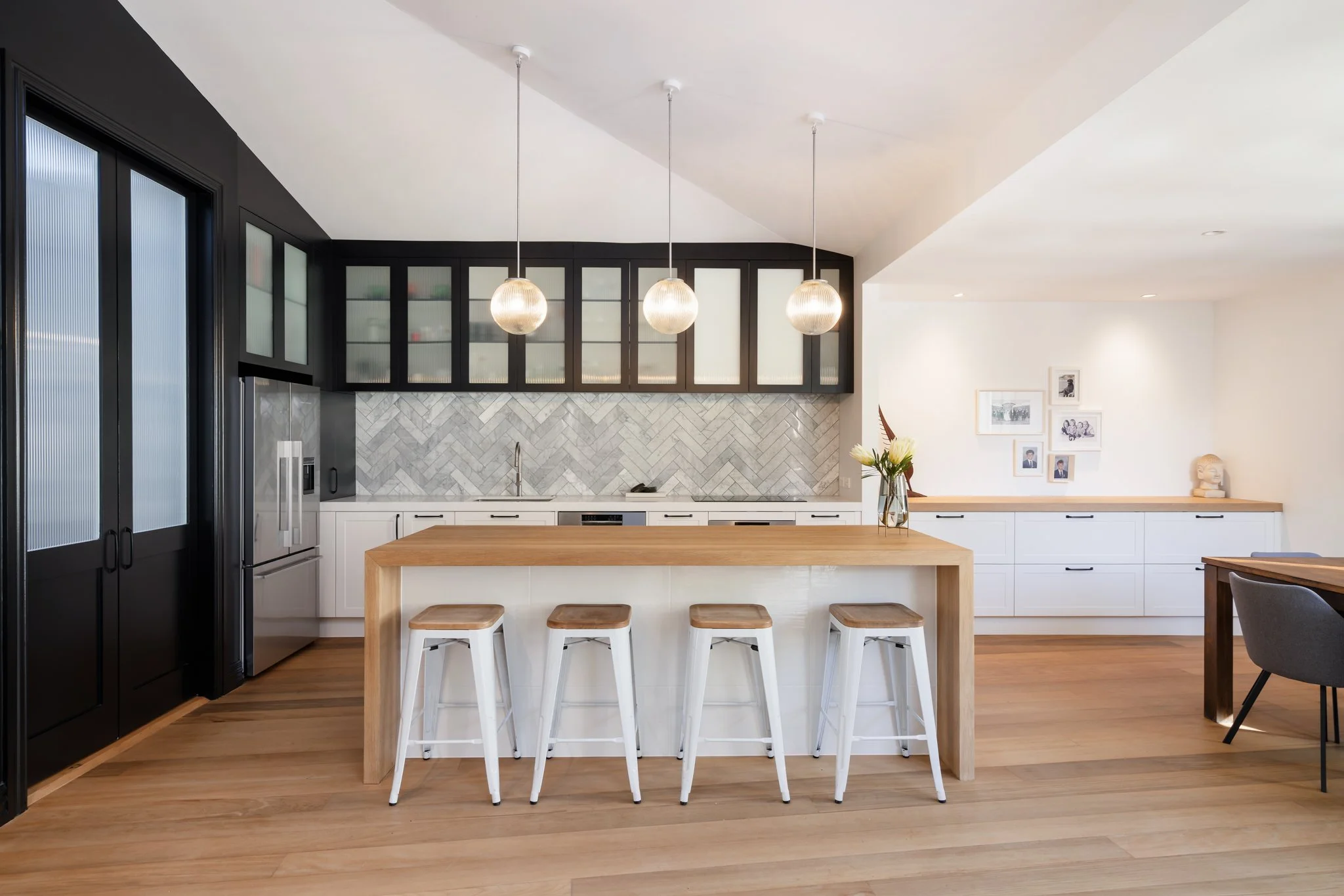 Freemans Bay double villa renovation new kitchen — vaulted ceiling, reeded glass cabinetry, marble herringbone splashback and oak island by Macfie Architecture Auckland