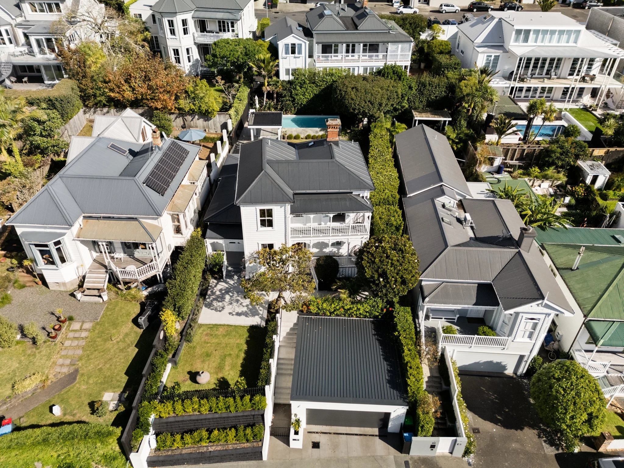 Aerial view of Freemans Bay double villa renovation — double garage, retaining-walled front garden and pool visible from above by Macfie Architecture Auckland