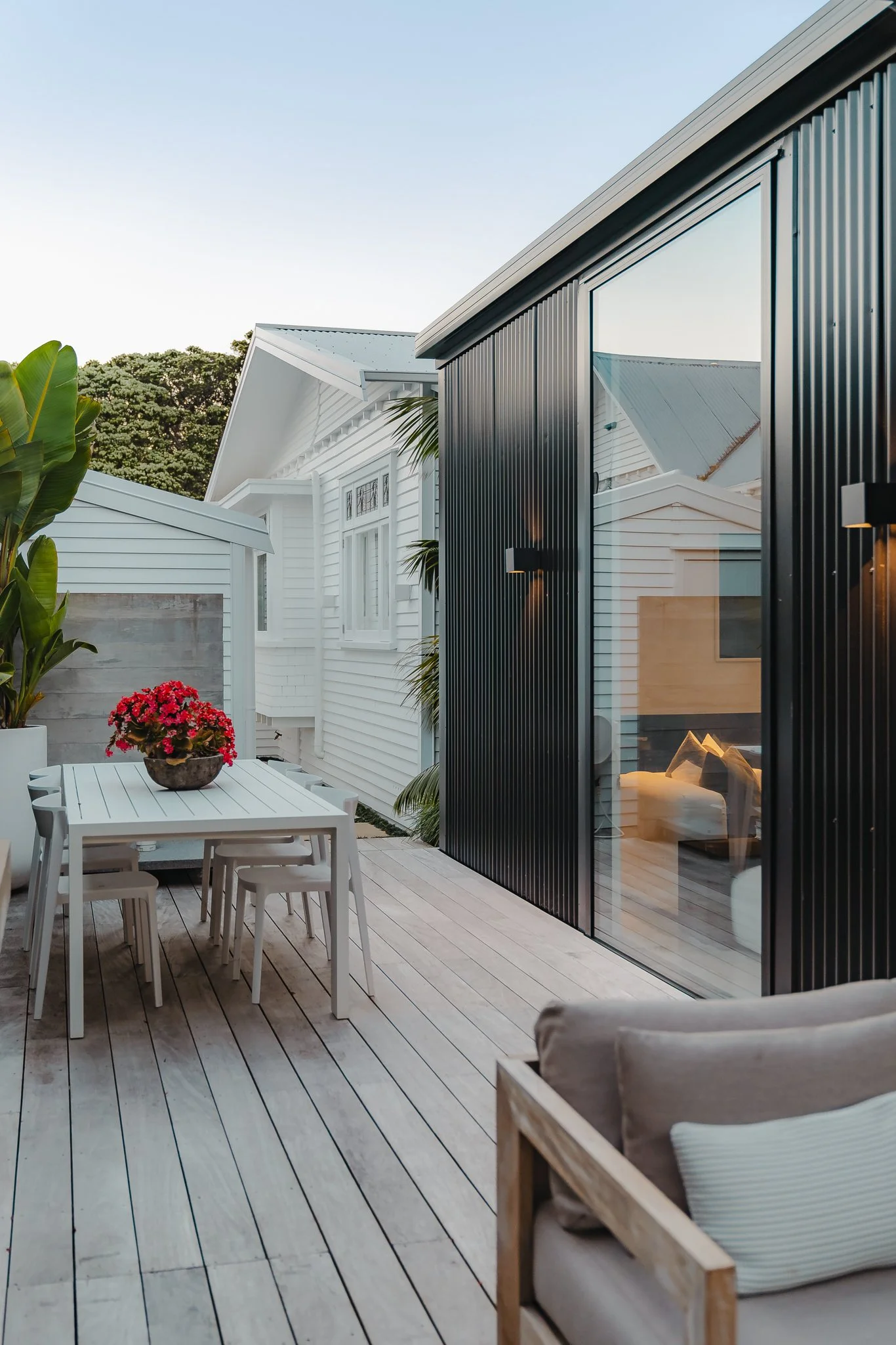 Contemporary black extension and deck alongside the original weatherboard bungalow, Point Chevalier Transitional Bungalow by Macfie Architecture