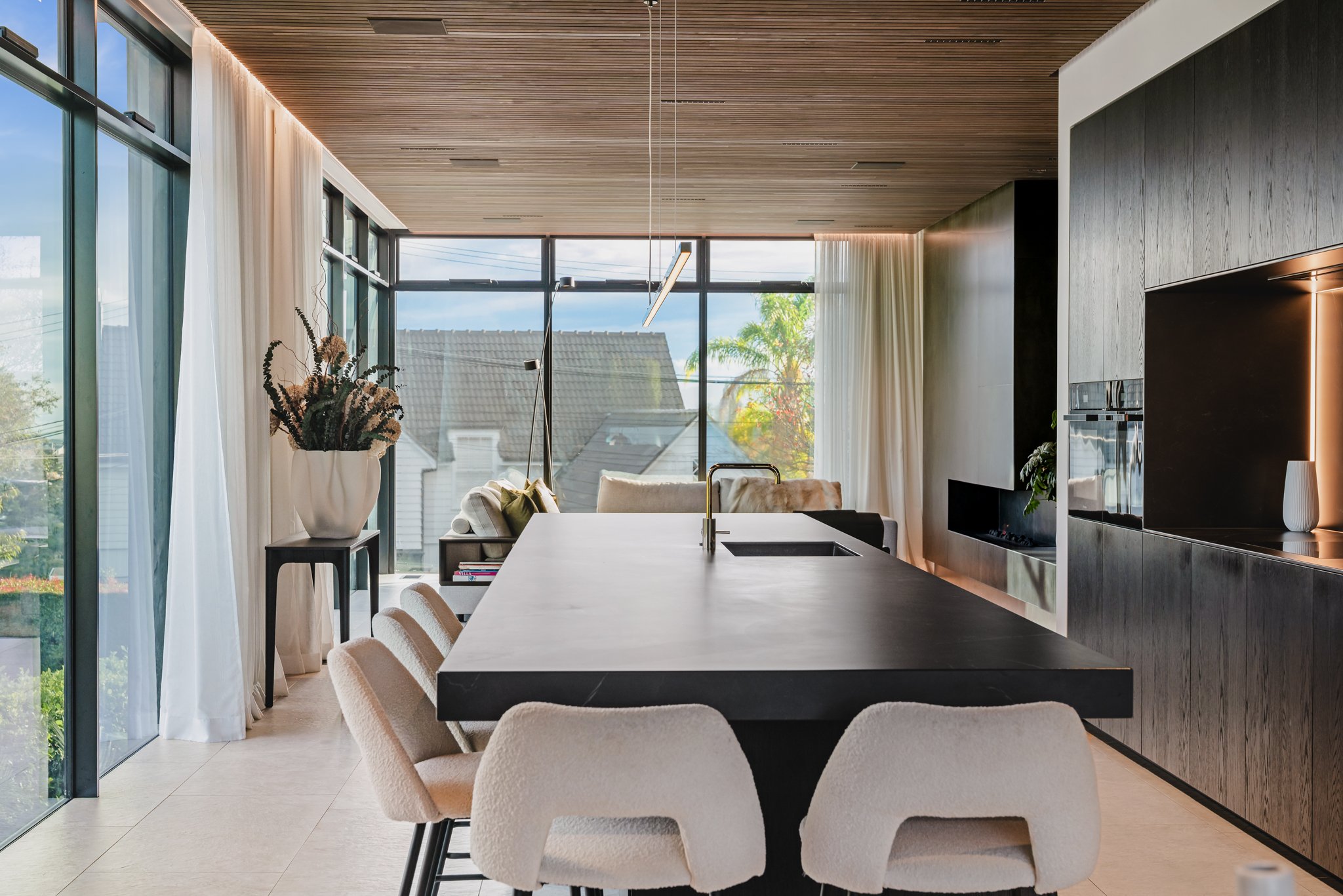 Bespoke new-build design with designer kitchen dark stone bench running the full length of the room, with blackened oak cabinetry below and a concealed scullery behind and a pendant