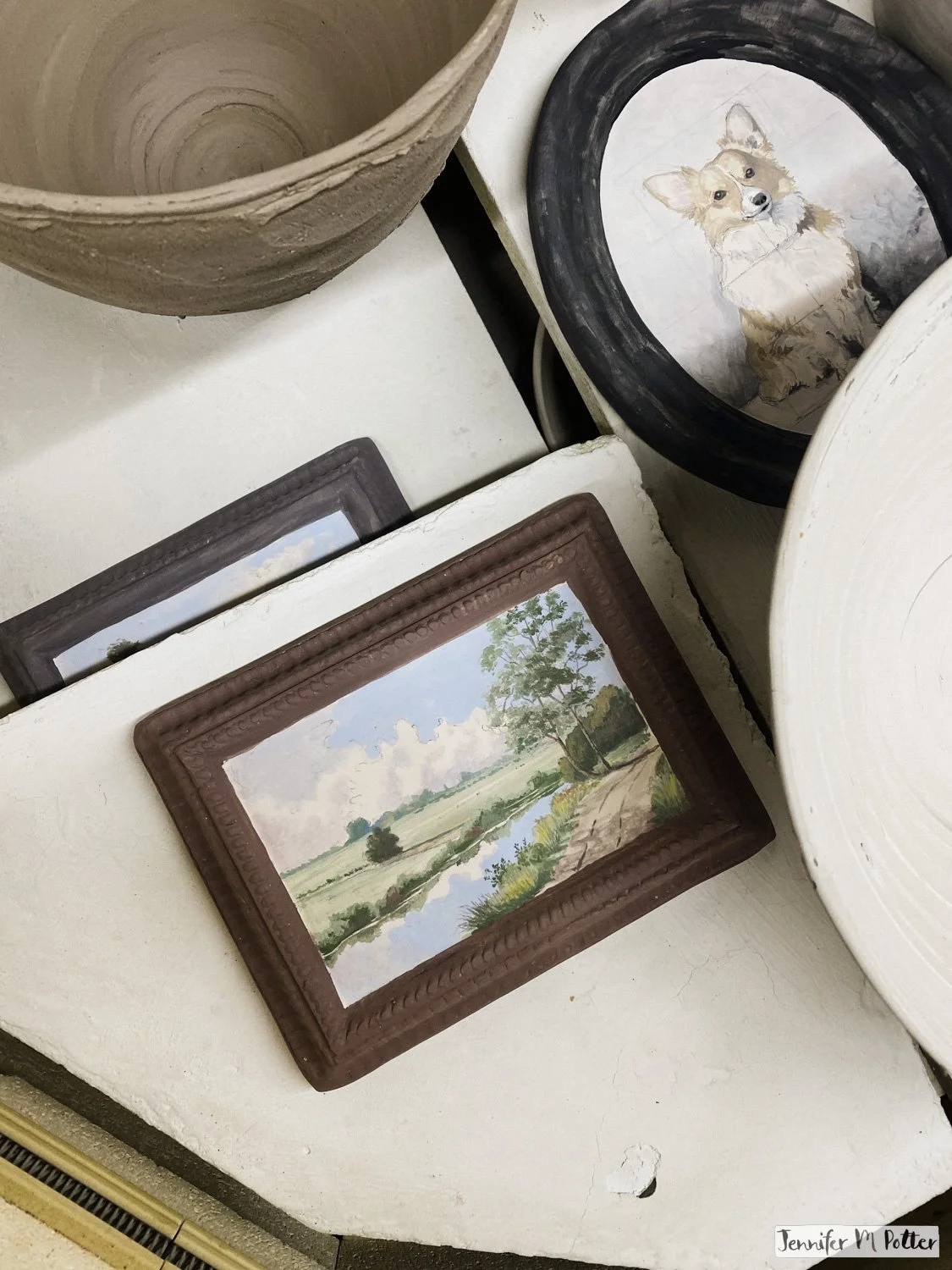Layers of pottery, including a few ceramic framed paintings, in the kiln