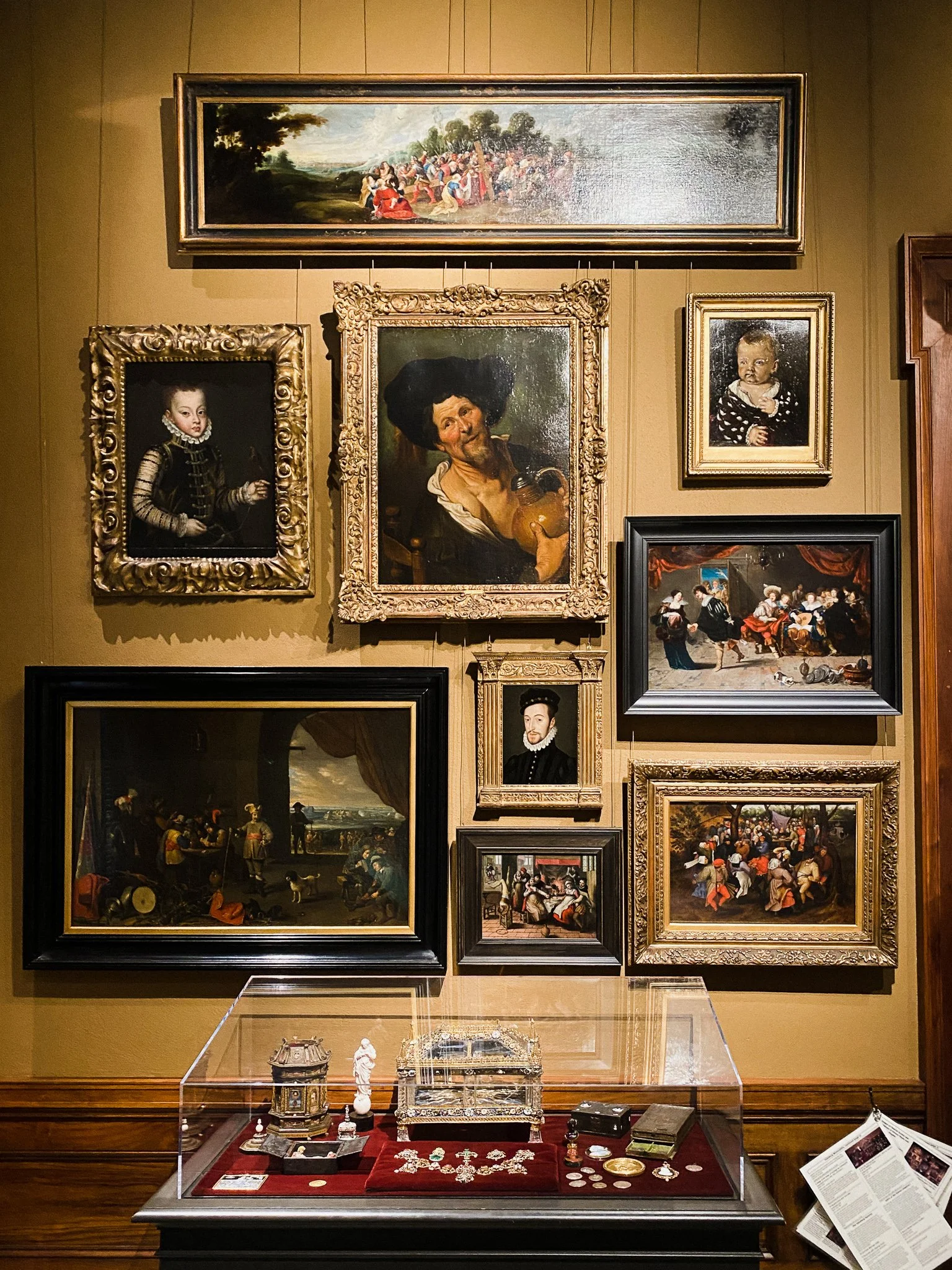 A gallery wall at the Walters Art Museum of a variety of paintings of different sizes, some showing portraits, others showing more complex scenes