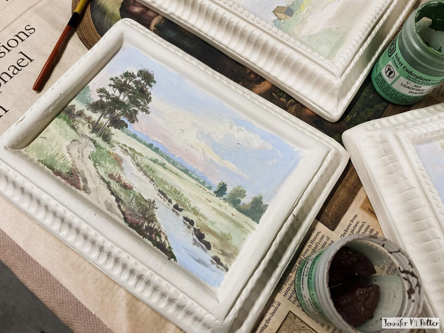 Painting a detailed landscape on the bisque canvases.
