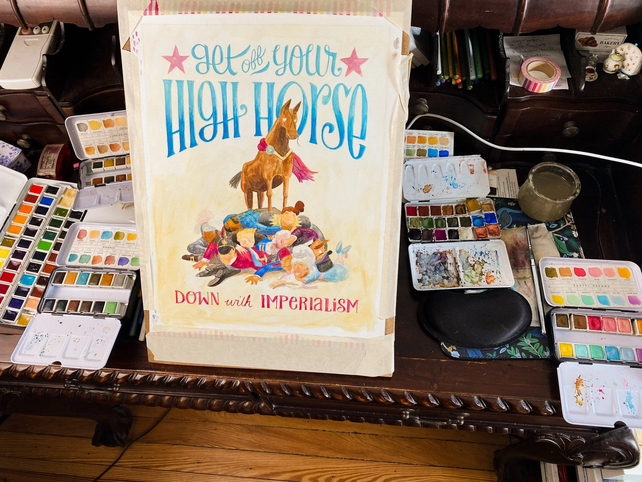 Work in progress of the illustration on a desk surrounded by multiple watercolor palettes