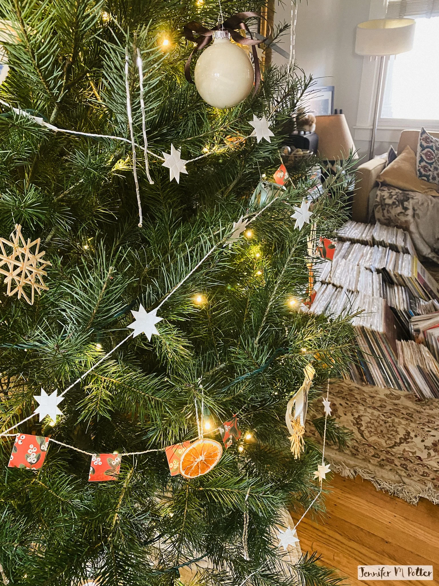 Decorated Christmas tree in living room with stacks of vinyl records nearby