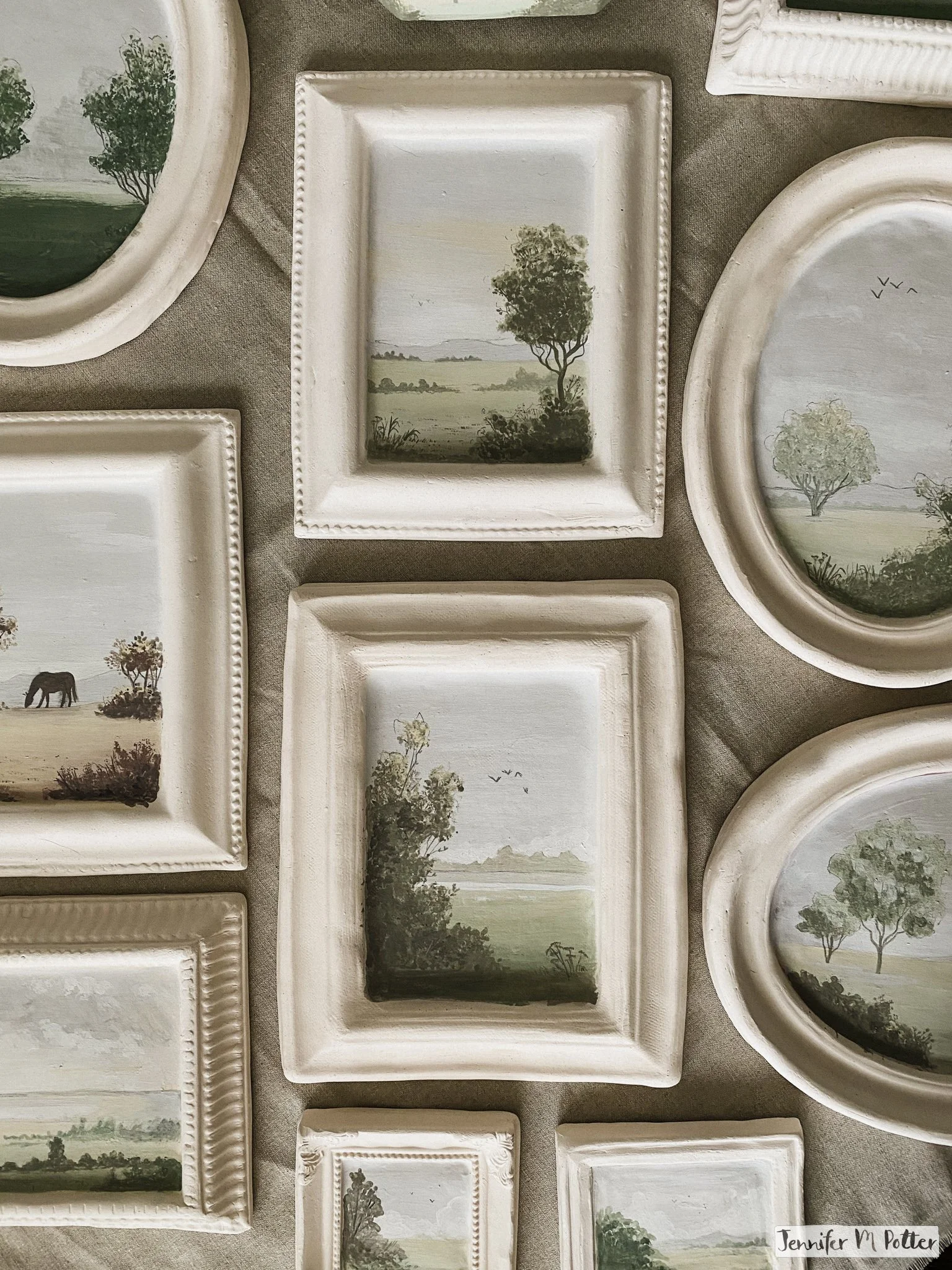 Several landscape paintings on unfired bisqueware.