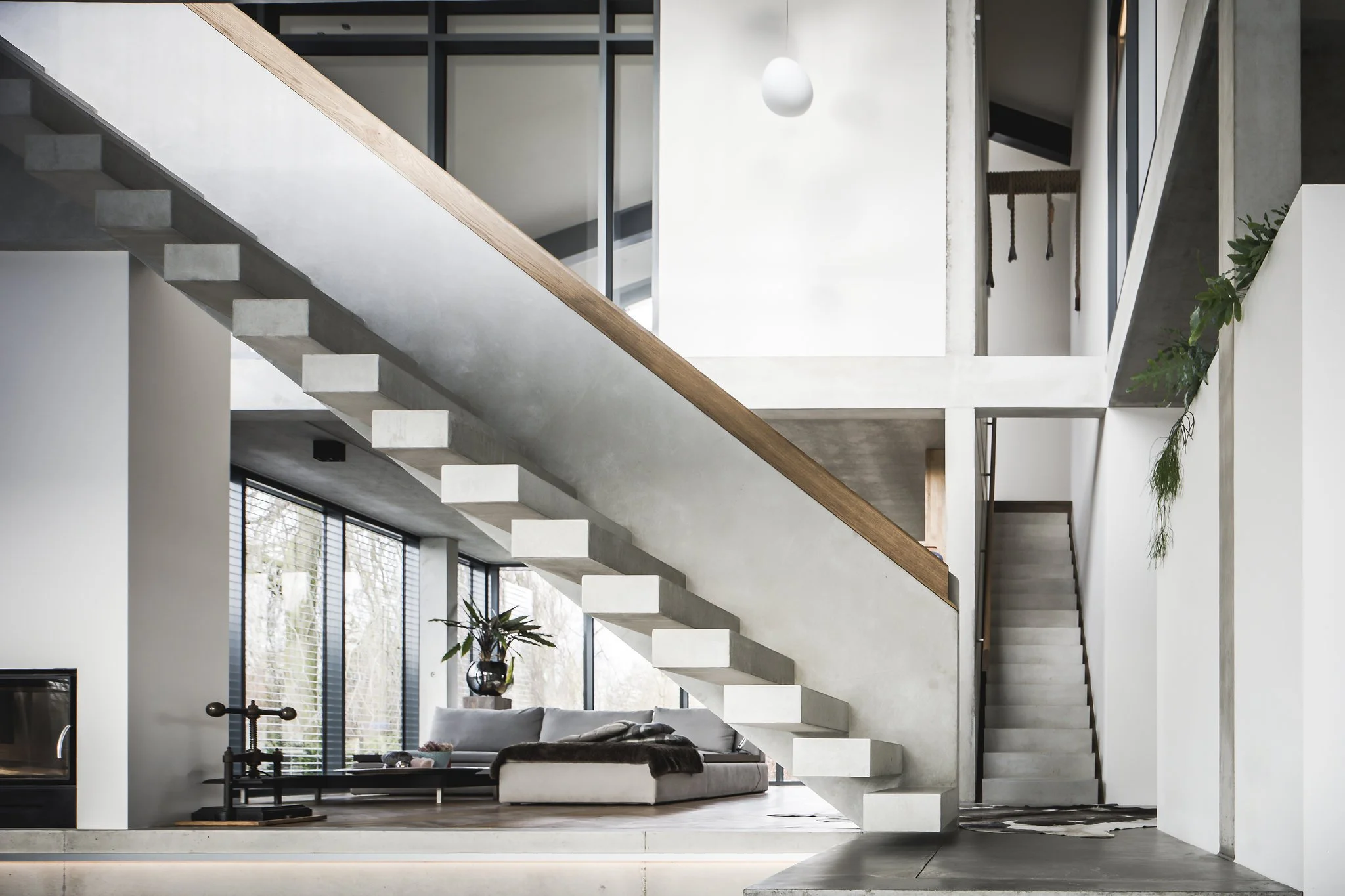 Loft style interior living room with concrete staircase, large windows, and minimal decor.