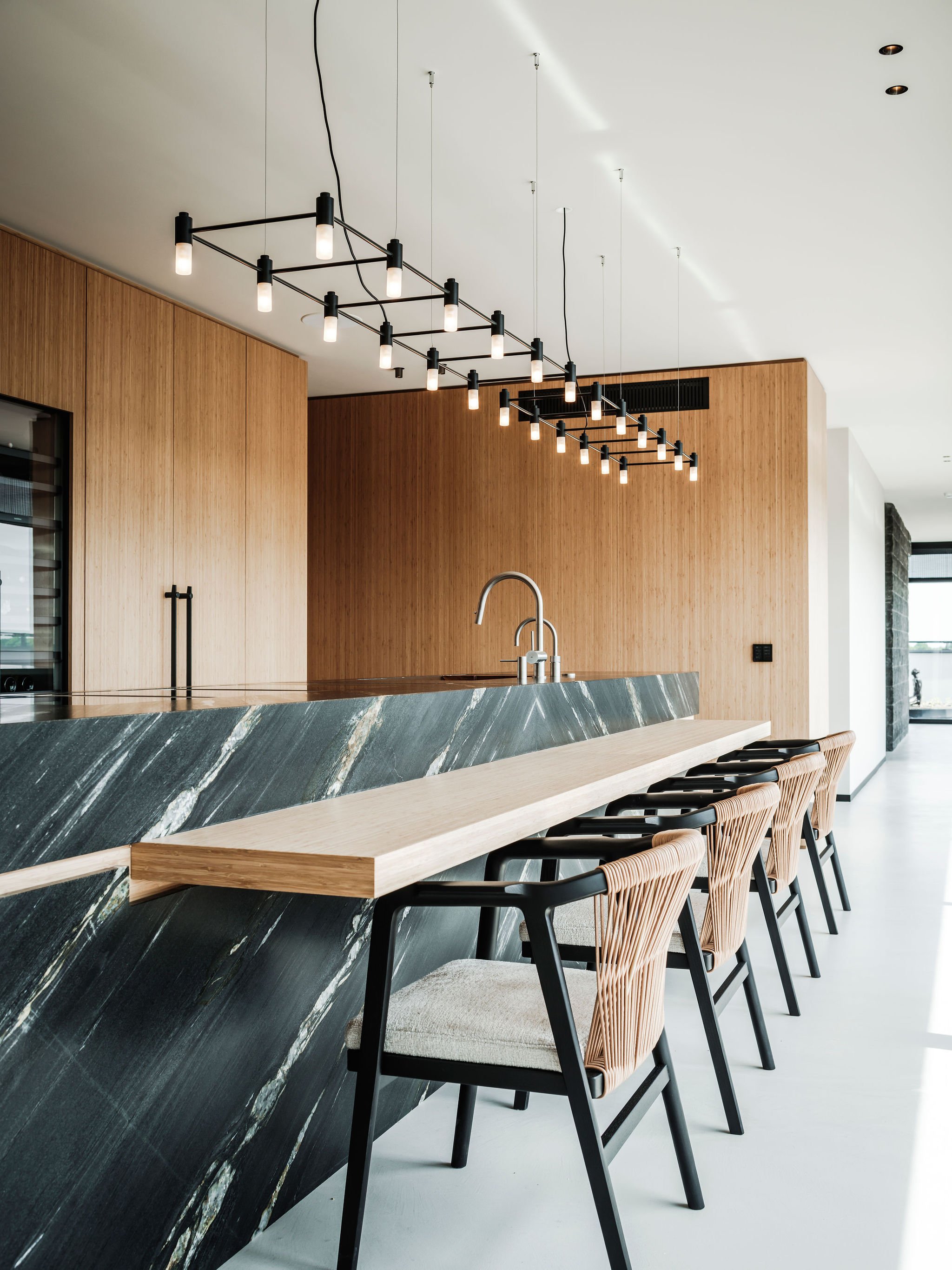 Modern Japanese kitchen with a black marble countertop, wooden cabinets, and a row of barstools.