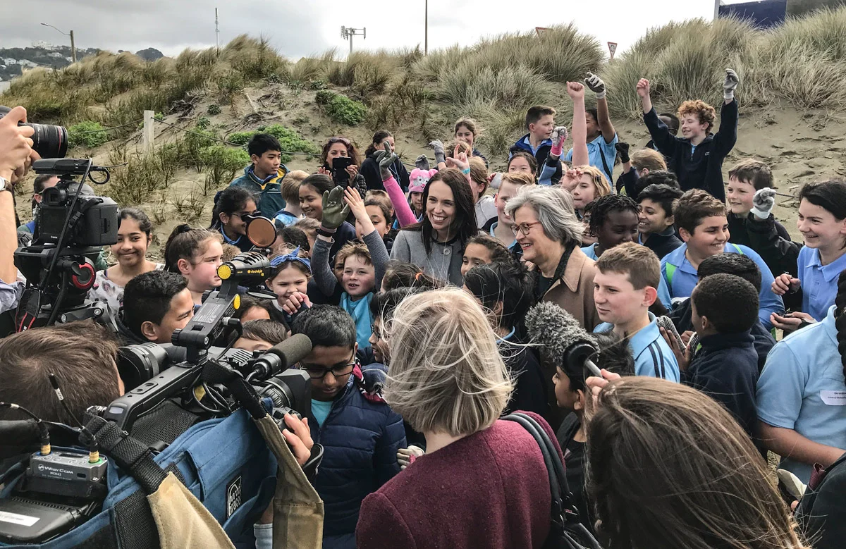 PM Jacinda Ardern and Associate Environment Minister Eugenie Sage celebrate the announcement by joining the kids for a beach clean-up.