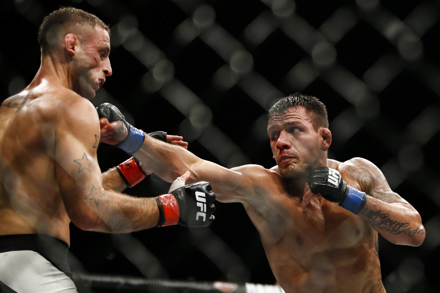 Rafael dos Anjos (R) of Brazil punches Tarec Saffiedine of Belgium during their welterweight bout at the UFC Fight Night at the Singapore Indoor Stadium on June 17, 2017.