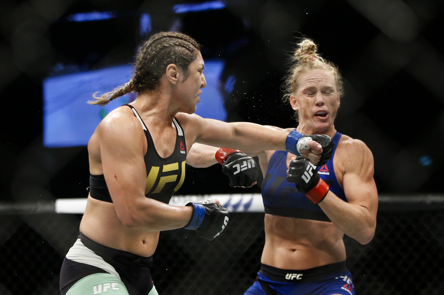 Bethe Correia (L) of Brazil punches Holly Holm of the United States during their bantamweight bout at the UFC Fight Night at the Singapore Indoor Stadium on June 17, 2017.