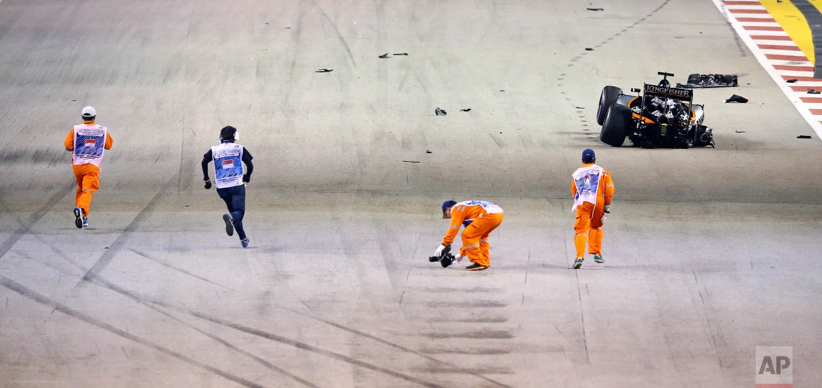 Track marshals clear debris from the track after Force India driver Nico Hulkenberg of Germany crashed at the start of the Singapore Formula One Grand Prix on the Marina Bay City Circuit in Singapore, Sunday, Sept. 18, 2016. (AP Photo/Yong Teck Lim)