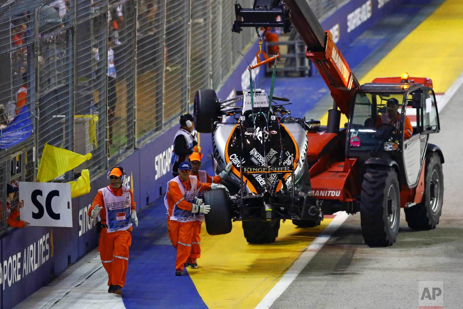 The car of Force India driver Nico Hulkenberg of Germany is taken from the track after he crashed at the start of the Singapore Formula One Grand Prix on the Marina Bay City Circuit in Singapore, Sunday, Sept. 18, 2016. (AP Photo/Yong Teck Lim)