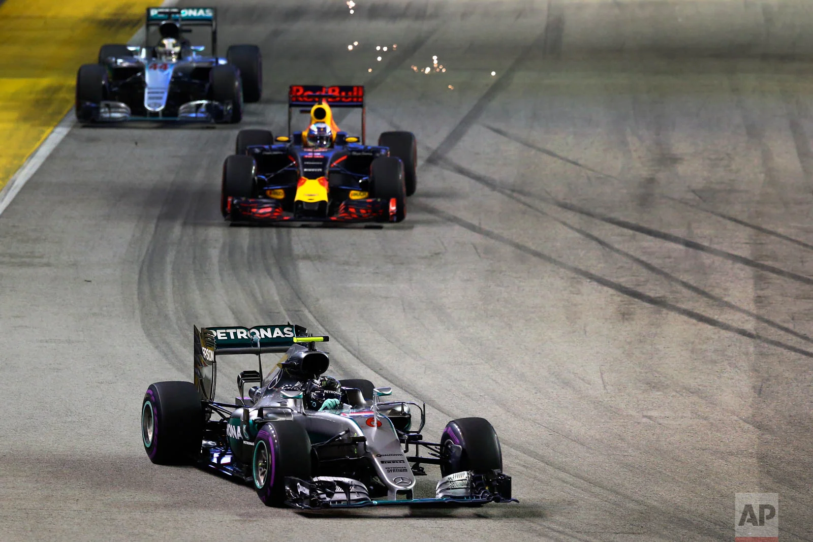 Mercedes driver Nico Rosberg of Germany, followed by Red Bull driver Daniel Ricciardo of Australia and Mercedes driver Lewis Hamilton of Britain, steer their cars during the Singapore Formula One Grand Prix on the Marina Bay City Circuit in Singapore, Sunday, Sept. 18, 2016. (AP Photo/Yong Teck Lim)