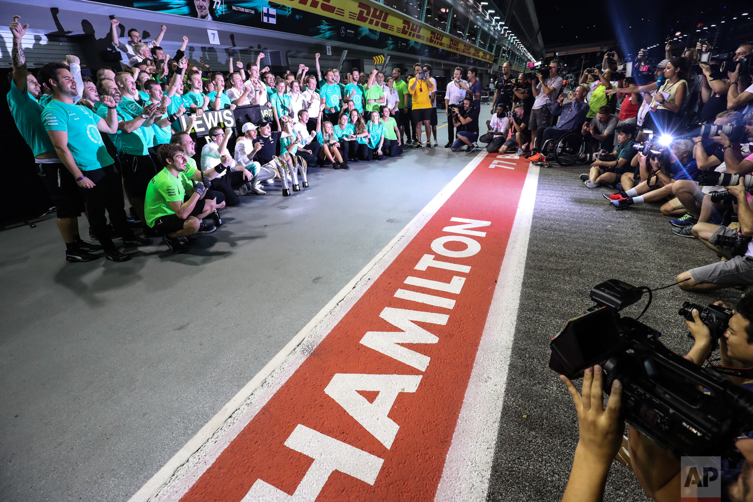  Mercedes driver Lewis Hamilton of Britain and Mercedes driver Valtteri Bottas of Finland celebrate with their team after the Singapore Formula One Grand Prix on the Marina Bay City Circuit Singapore, Sunday, Sept. 17, 2017. Hamilton won the race whi